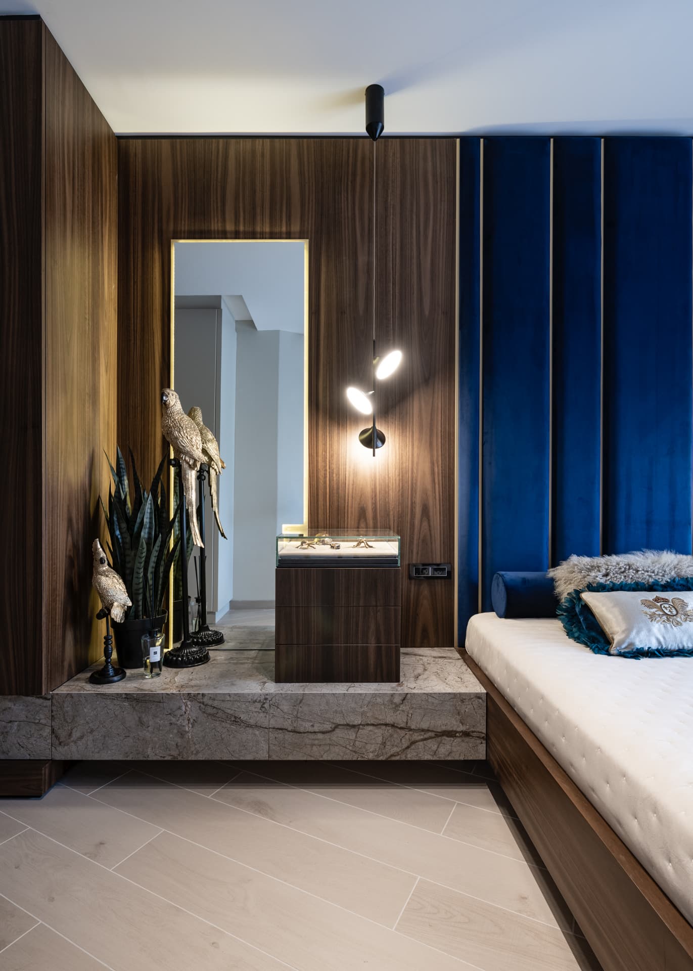 Warm evening light on the brass-framed mirror, stone plinth and velvet headboard edge in the master bedroom of Argamán
