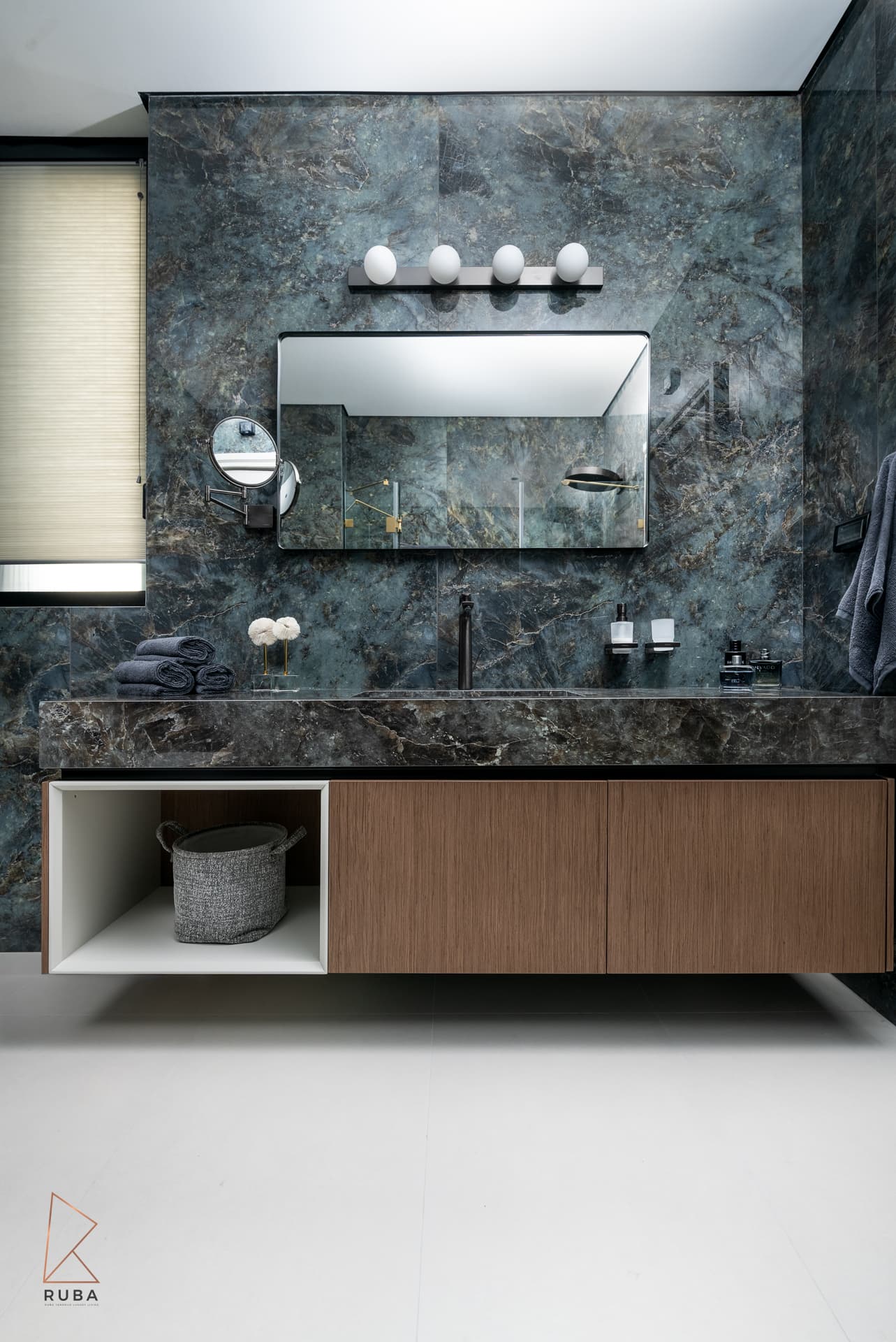 Floating wood vanity against a blue-green veined stone wall with globe lights in the second bathroom of Bird of Paradise Flower