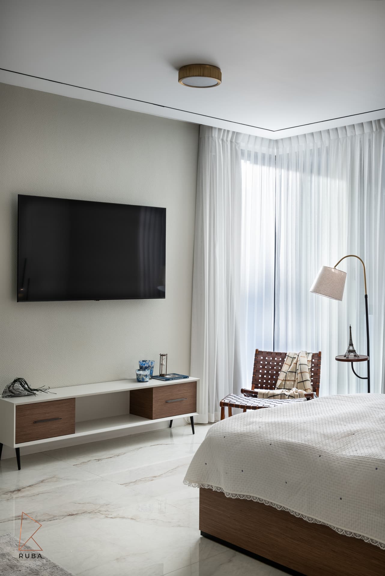 Wall-mounted screen over a white-and-wood media console, with the reading corner beyond, in the second bedroom of Bird of Paradise Flower