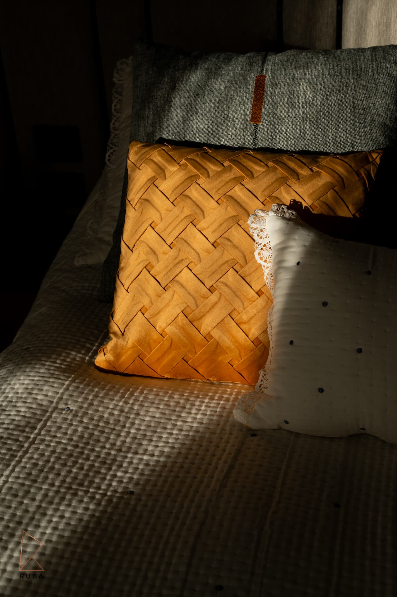 Ochre basket-weave cushion and lace-trimmed white pillow in a shaft of sunlight in the second bedroom of Bird of Paradise Flower