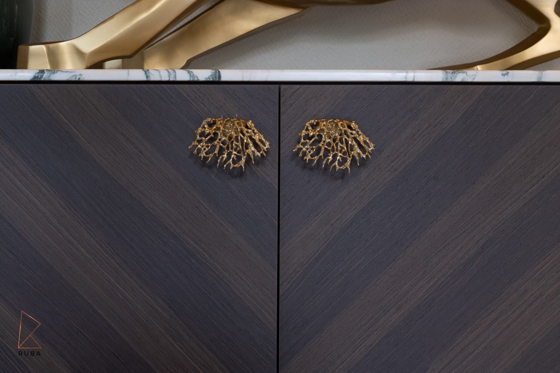 Coral-shaped brass pulls on chevron-veneered dark wood sideboard doors under a marble top in Bird of Paradise Flower