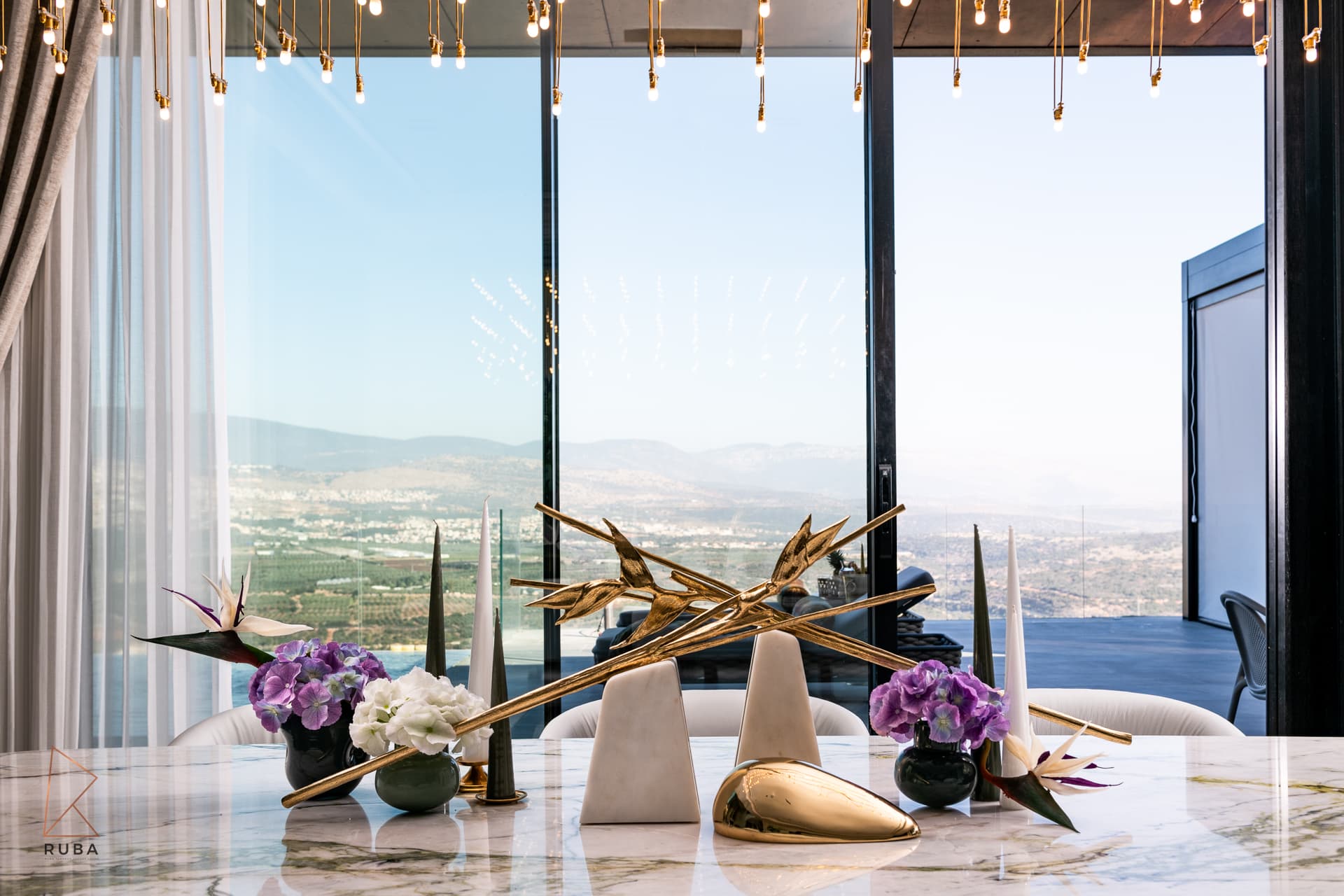 Gold bird-of-paradise sculpture, tall cone ornaments and purple flowers on the marble table in the dining room of Bird of Paradise Flower