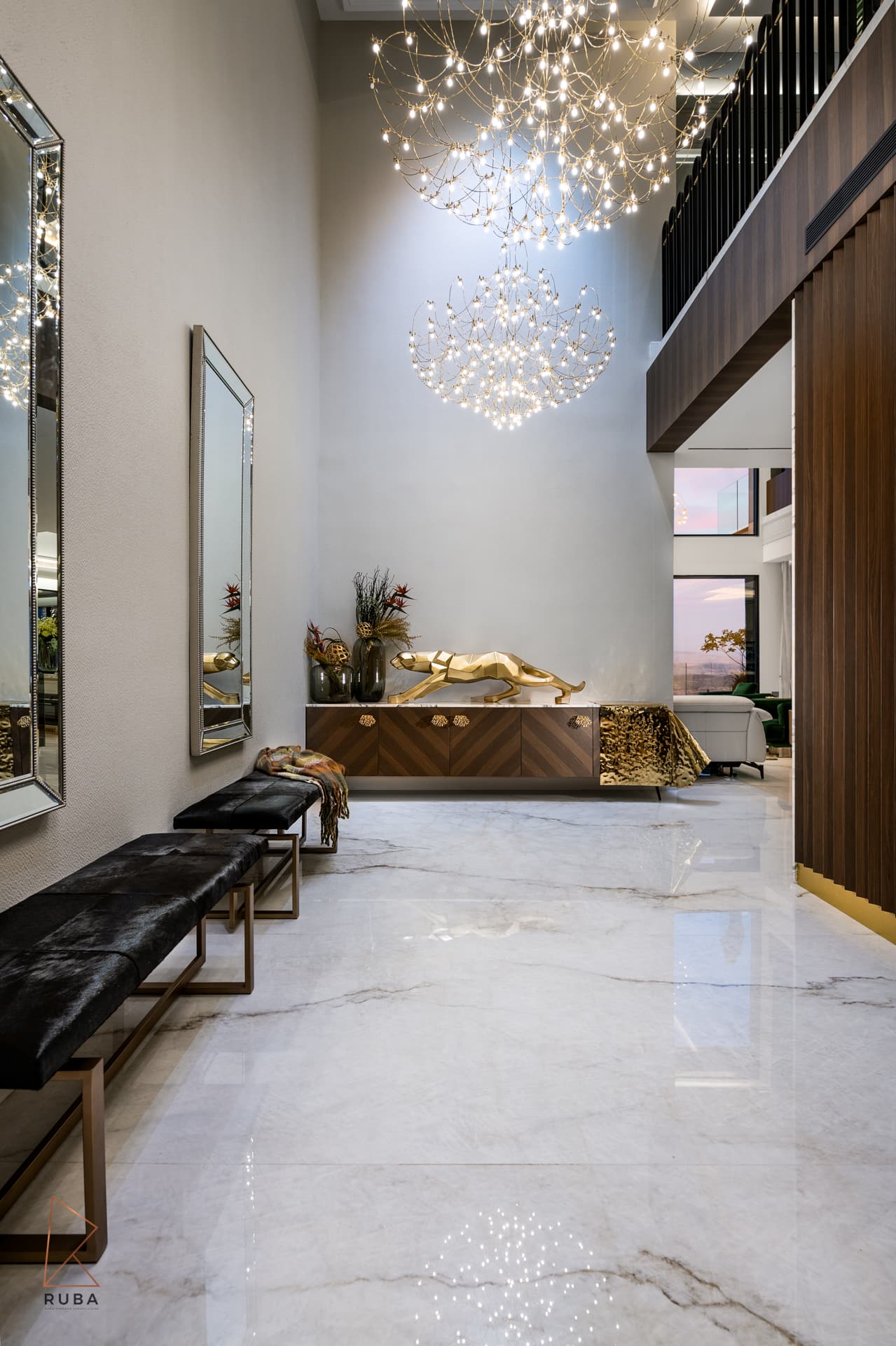 Double-height entrance hall with cascading wire chandeliers, tall framed mirrors and black hide benches in Bird of Paradise Flower