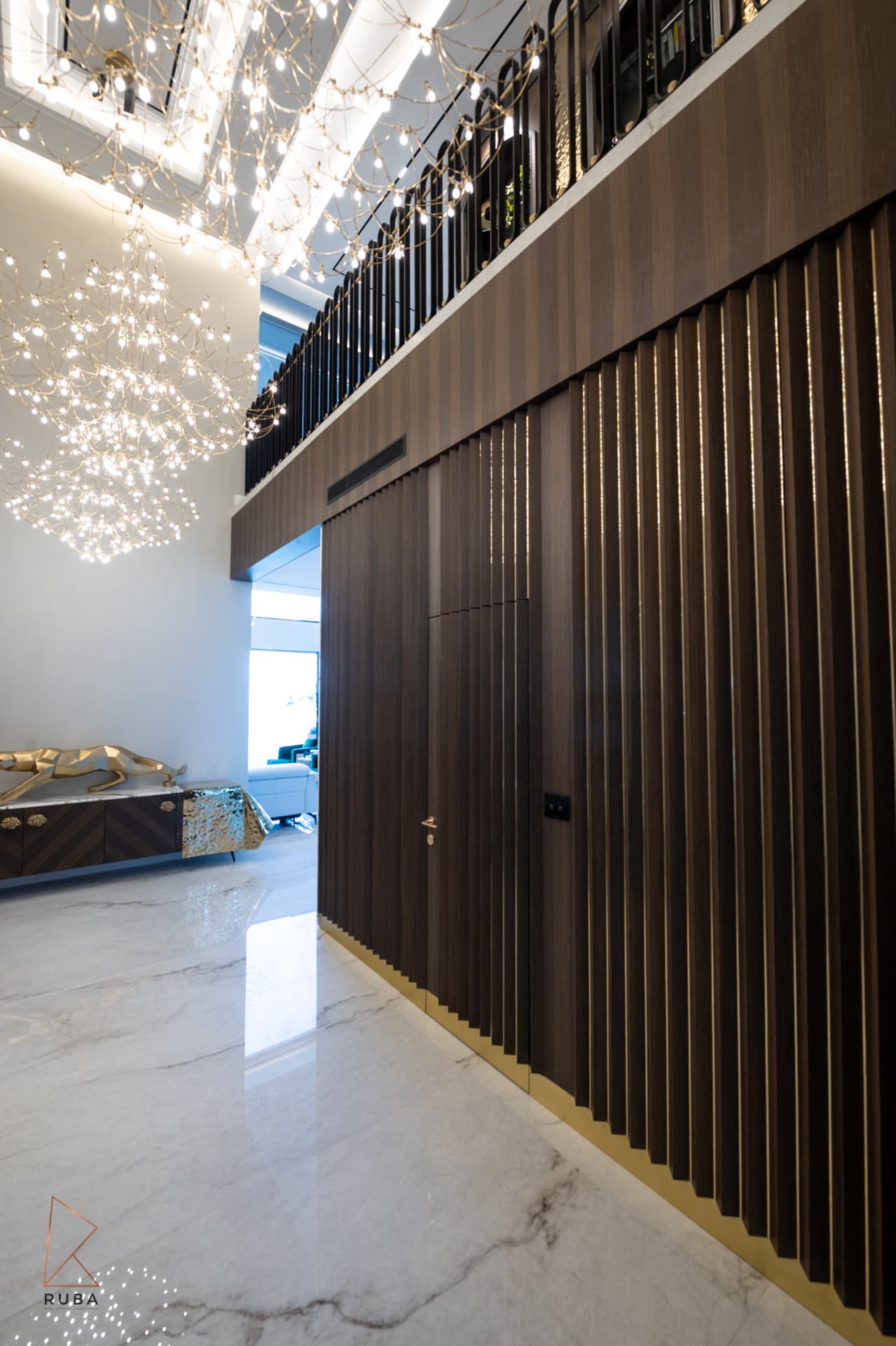 Pleated dark wood wall with a concealed door beneath the upper gallery railing in the entrance hall of Bird of Paradise Flower