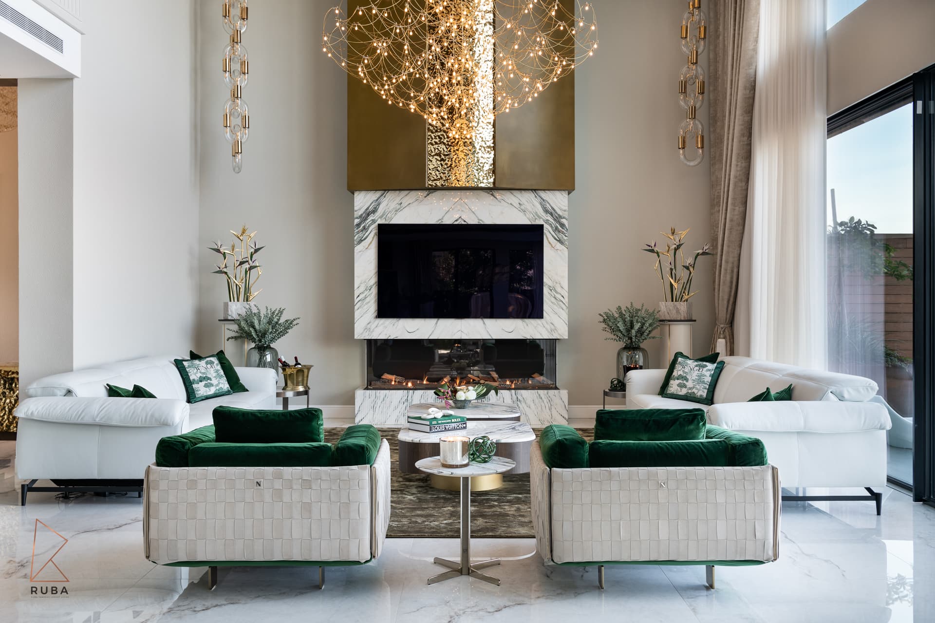 Landscape view of the veined marble fireplace framed by woven-back green velvet armchairs in the living room of Bird of Paradise Flower