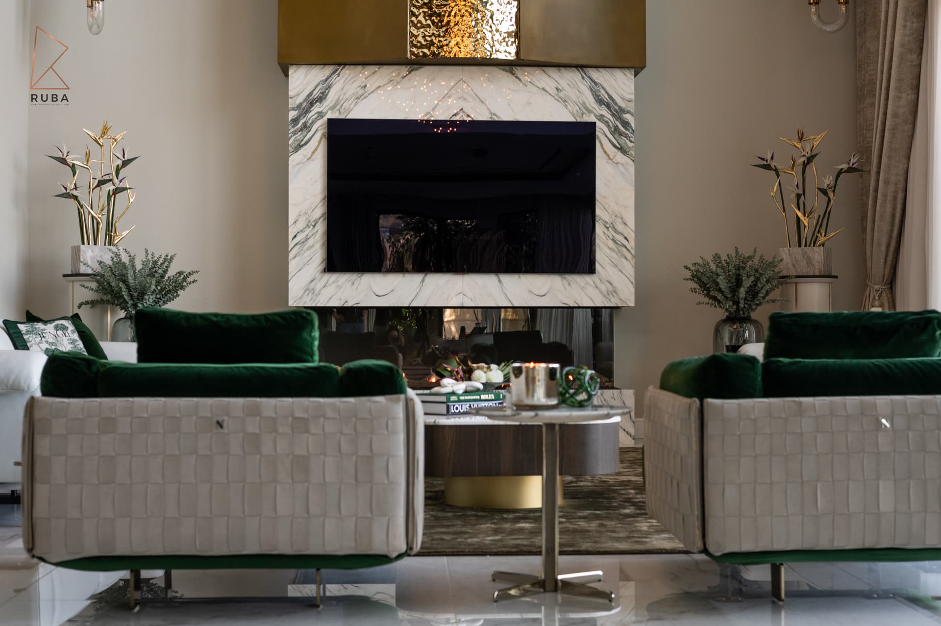 Eye-level view of two woven-back green velvet armchairs and a side table before the fireplace in the living room of Bird of Paradise Flower