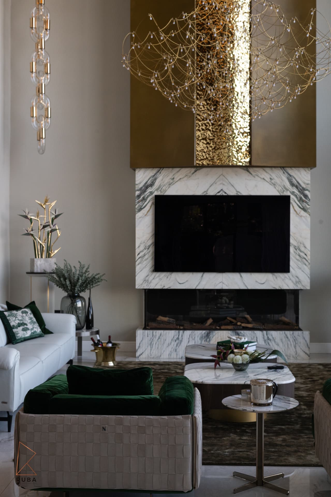 Portrait view of the marble fireplace under the hammered brass hood and wire chandelier in the living room of Bird of Paradise Flower