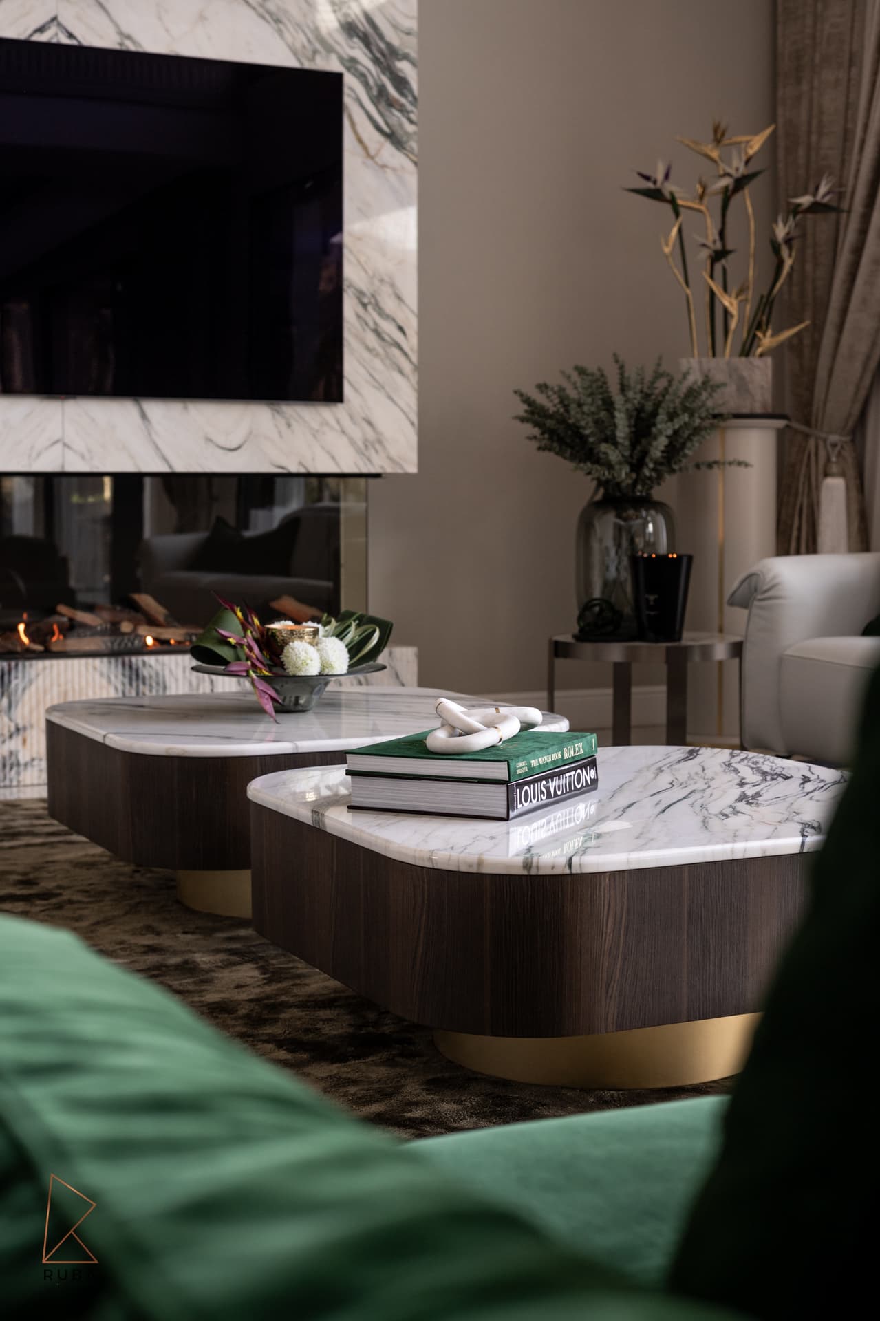 Marble-topped dark wood coffee tables with brass bases beside the fireplace in the living room of Bird of Paradise Flower