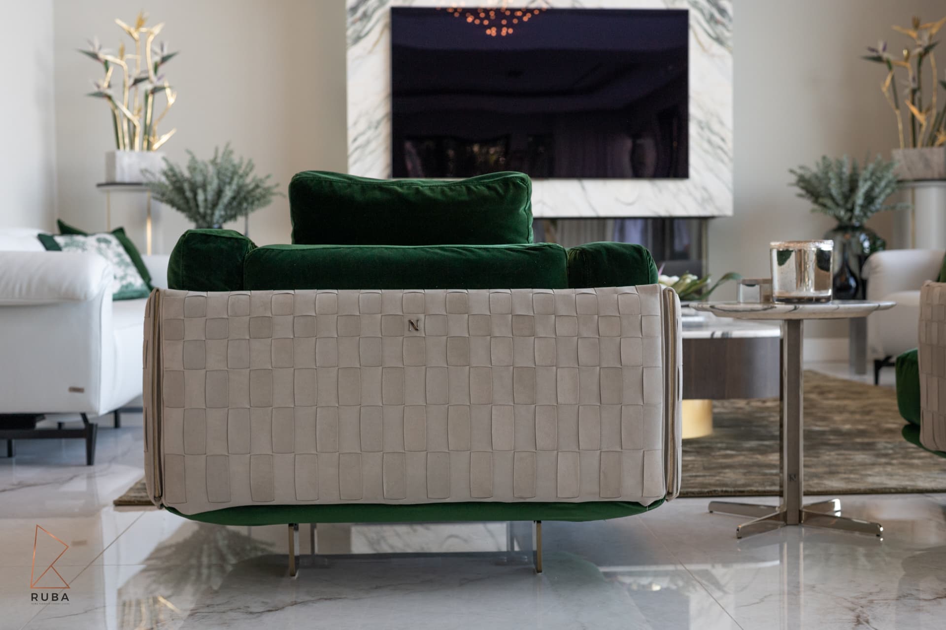 Back of a green velvet armchair with a woven leather shell, centred on the fireplace in the living room of Bird of Paradise Flower