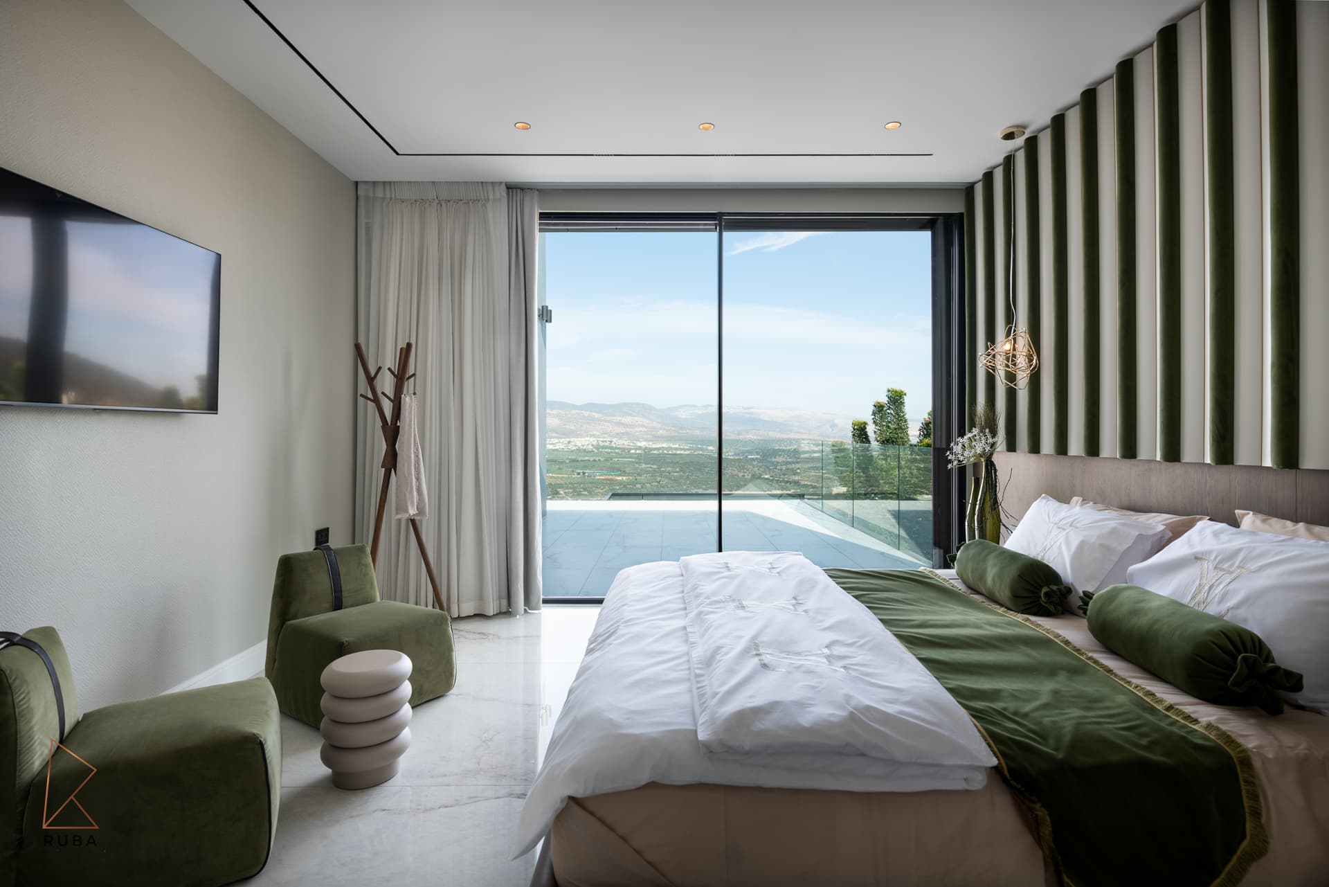 Master bedroom with a green-and-cream striped velvet wall, sage lounge chairs and a sliding door to the terrace in Bird of Paradise Flower