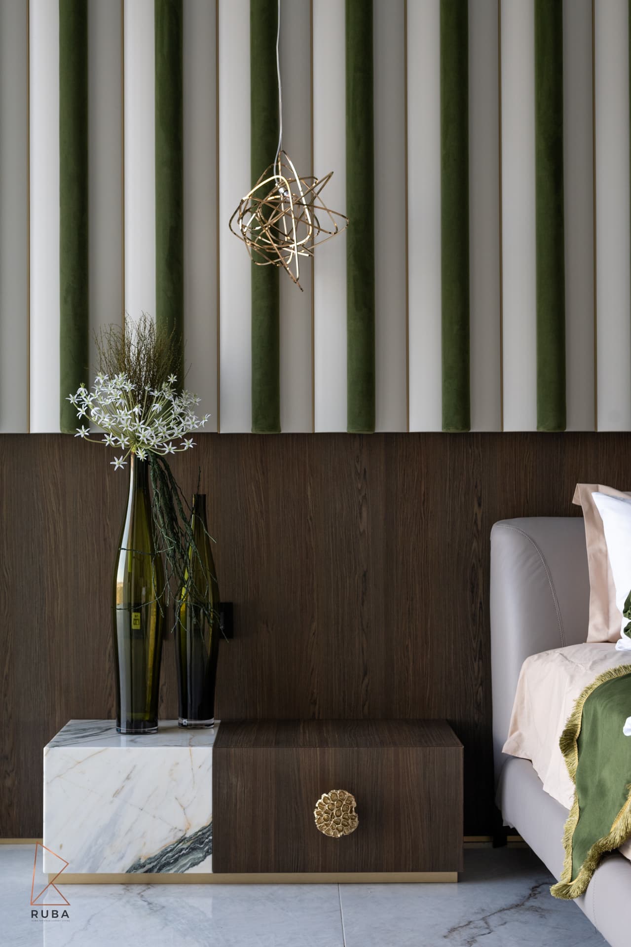 Split marble-and-wood nightstand under a gold wire pendant and striped velvet panels in the master bedroom of Bird of Paradise Flower