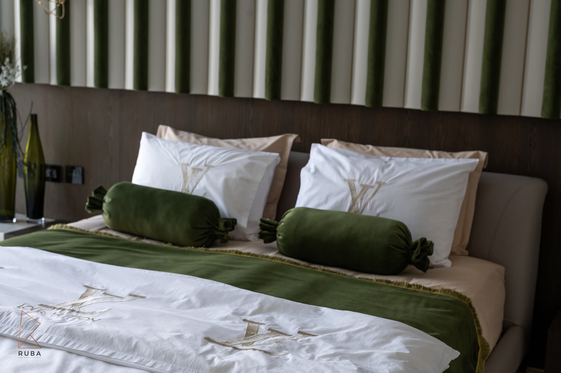 Green velvet bolster cushions and a fringed green throw on white embroidered bedding in the master bedroom of Bird of Paradise Flower