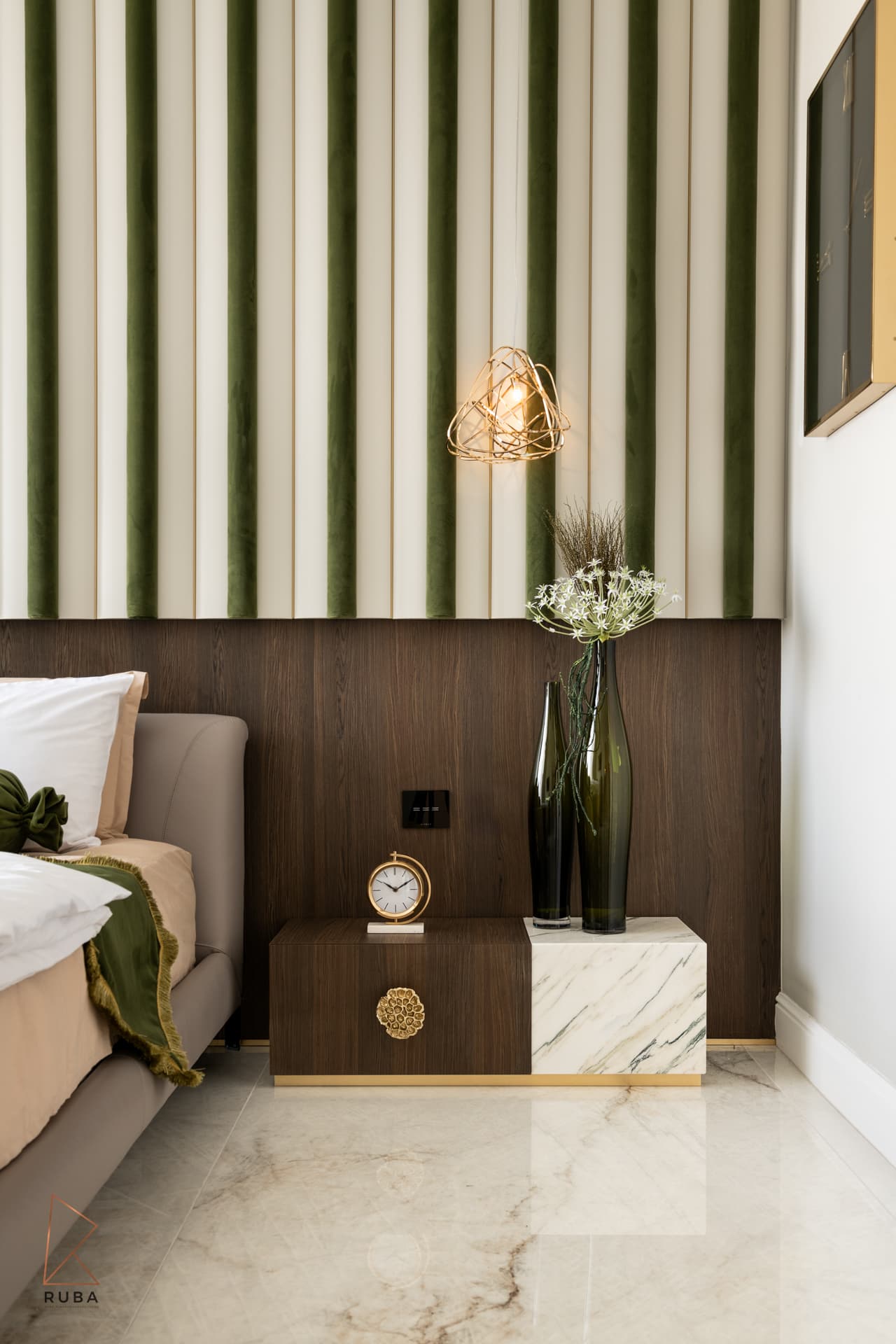 Nightstand with a brass clock and green glass vases below a lit gold wire pendant in the master bedroom of Bird of Paradise Flower