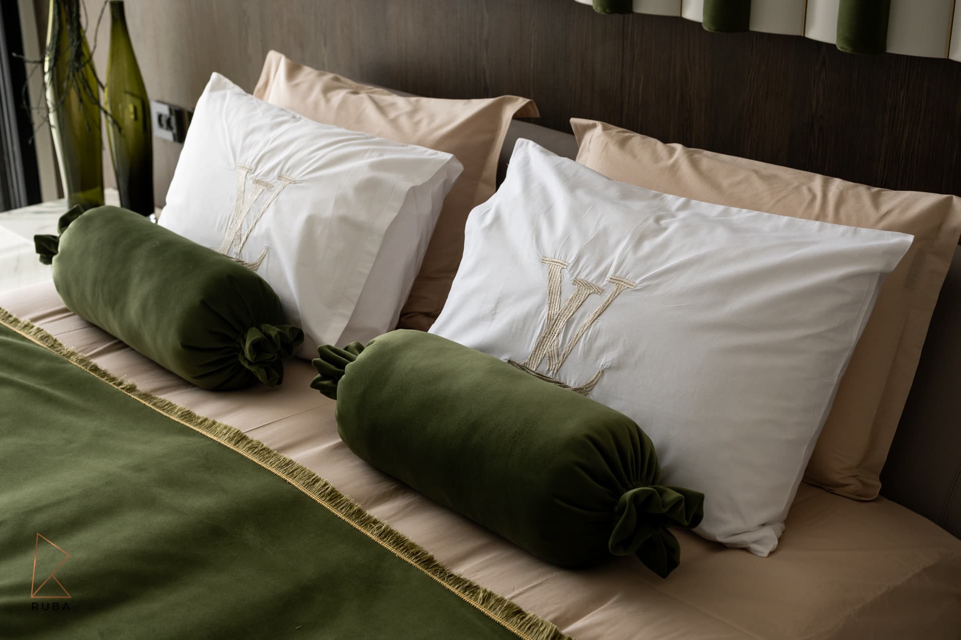 Close view of green velvet bolsters on layered white and beige pillows in the master bedroom of Bird of Paradise Flower