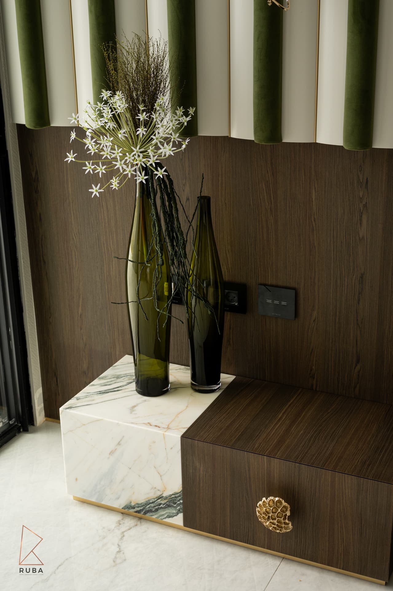 Tall green glass vases with white wildflowers on a marble-and-wood nightstand in the master bedroom of Bird of Paradise Flower