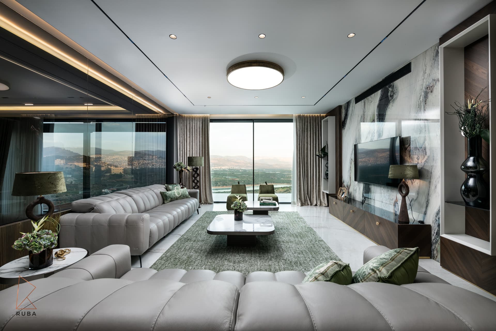 Salon with channel-tufted grey sofas, a green rug and a bookmatched marble media wall facing the valley view in Bird of Paradise Flower