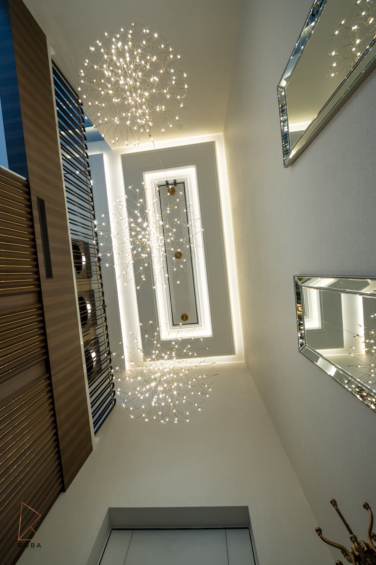 Upward view of the stairwell with wire sphere chandeliers under a backlit recessed ceiling panel in Bird of Paradise Flower