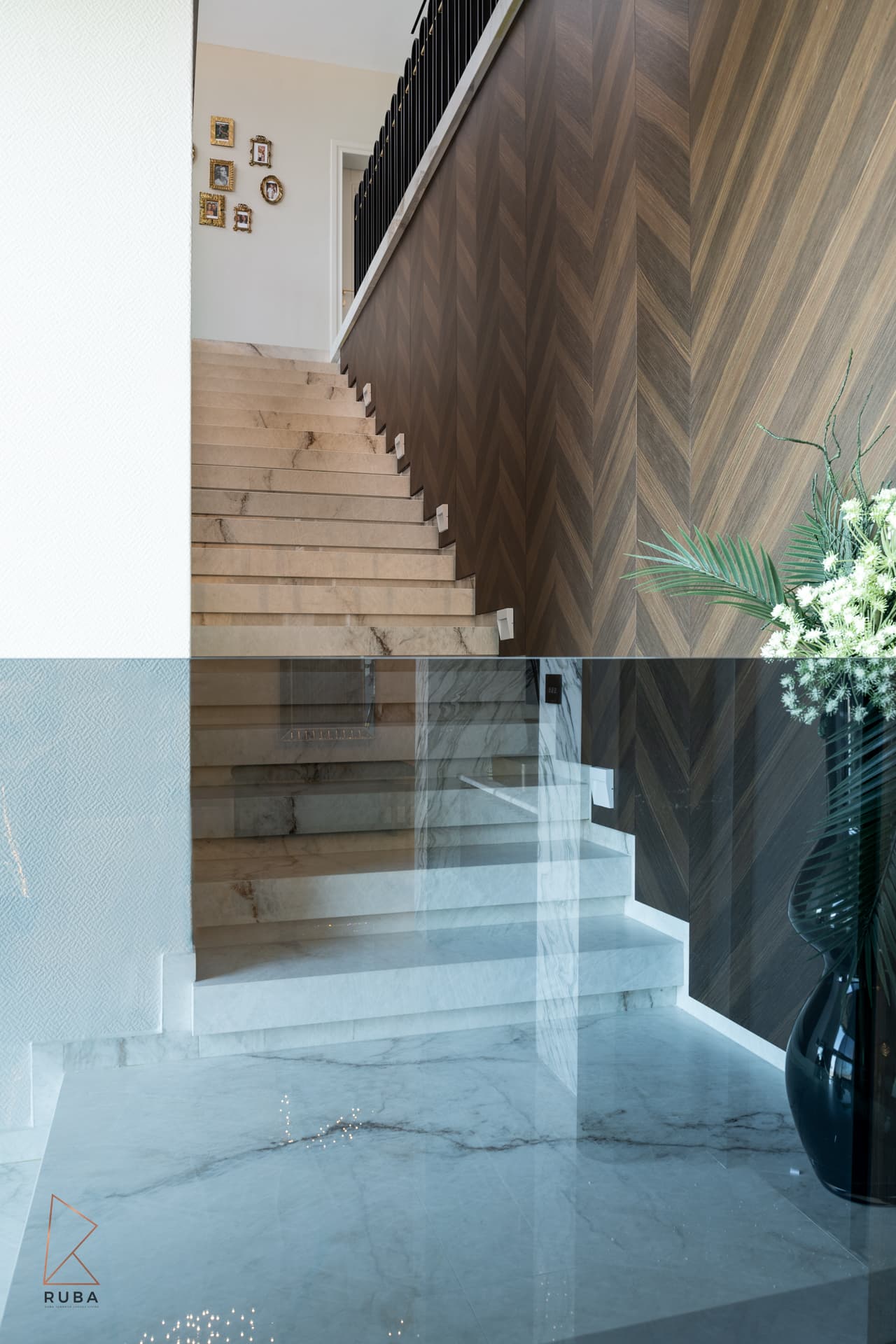 Pale stone staircase beside a chevron wood wall, seen through a glass balustrade, in Bird of Paradise Flower