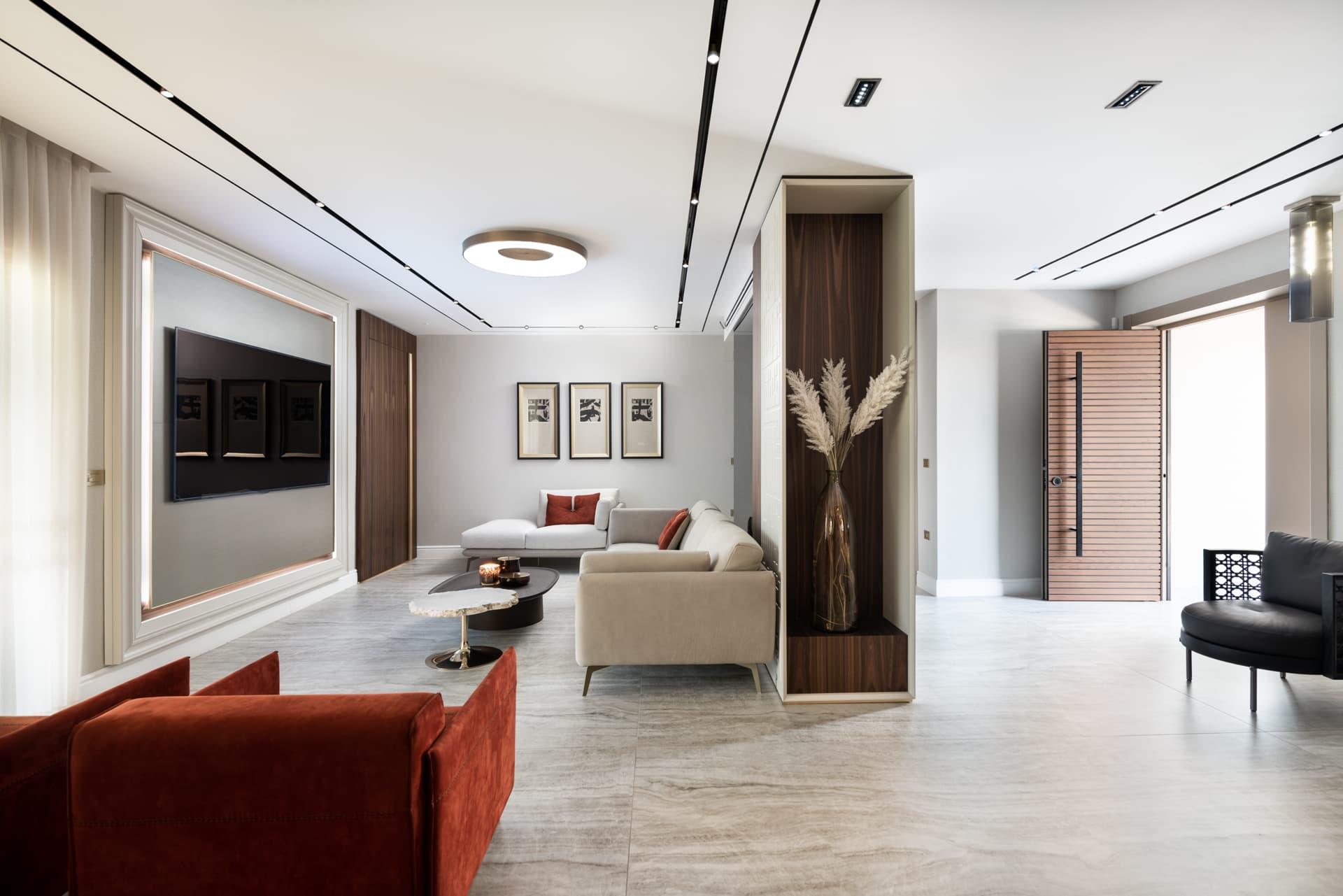 Open living room with a pair of rust velvet armchairs, walnut display niche and slatted wood entry door in Born Together