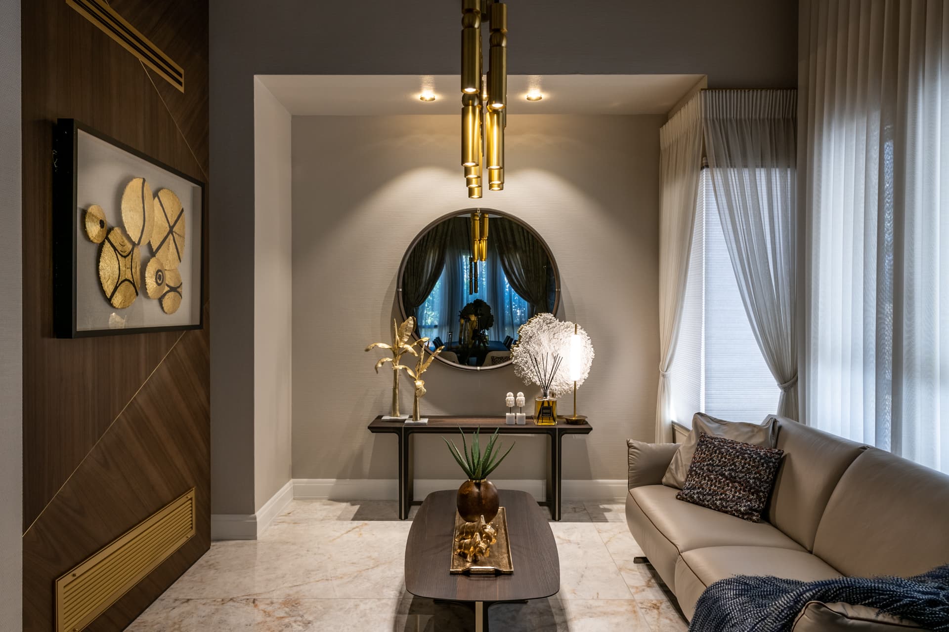 Eye-level view of the recessed round mirror and console flanked by a walnut wall panel and brass pendants in the salon of Cognac