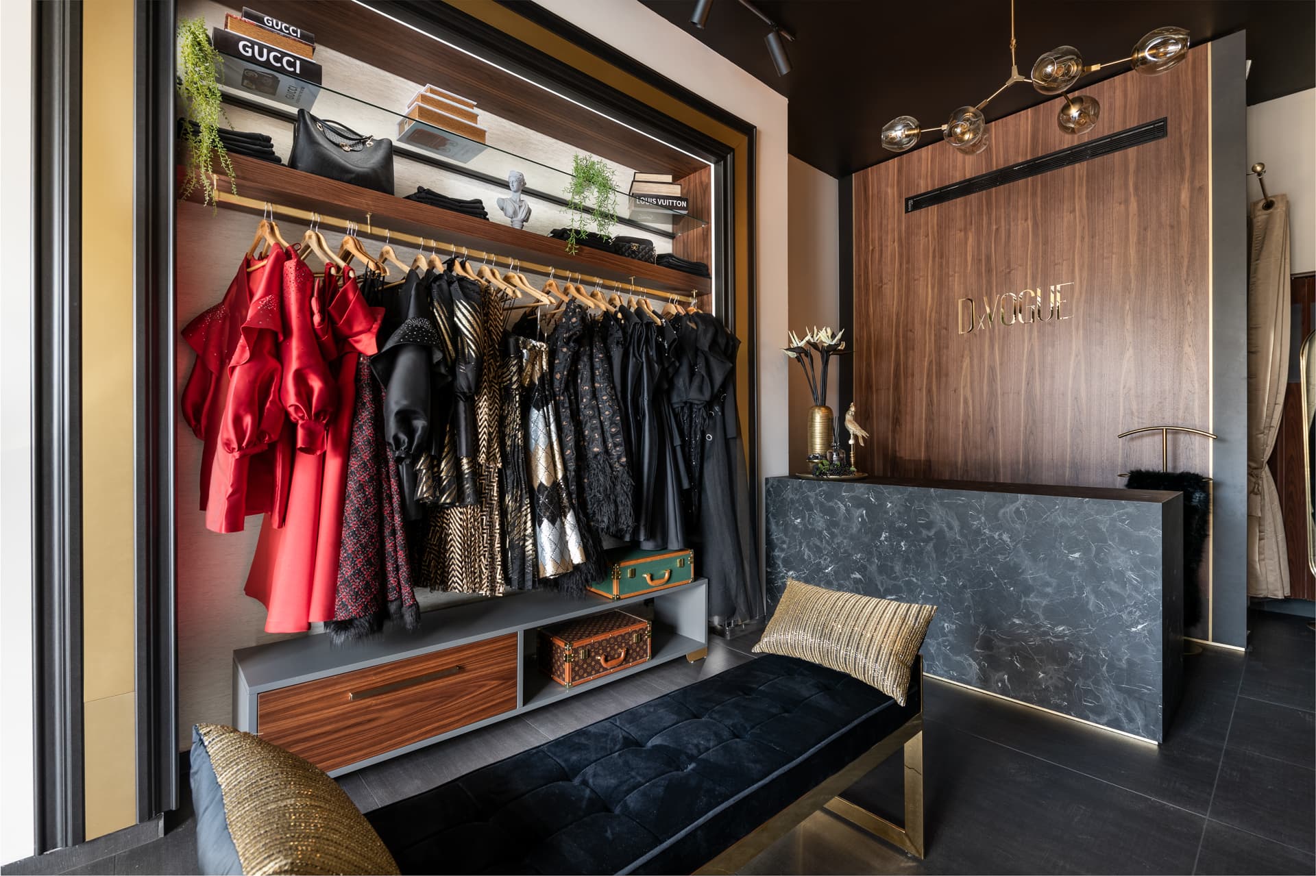 Angled view of a black velvet bench before a lit walnut wardrobe and a dark veined stone counter, in the showroom of DxVogue