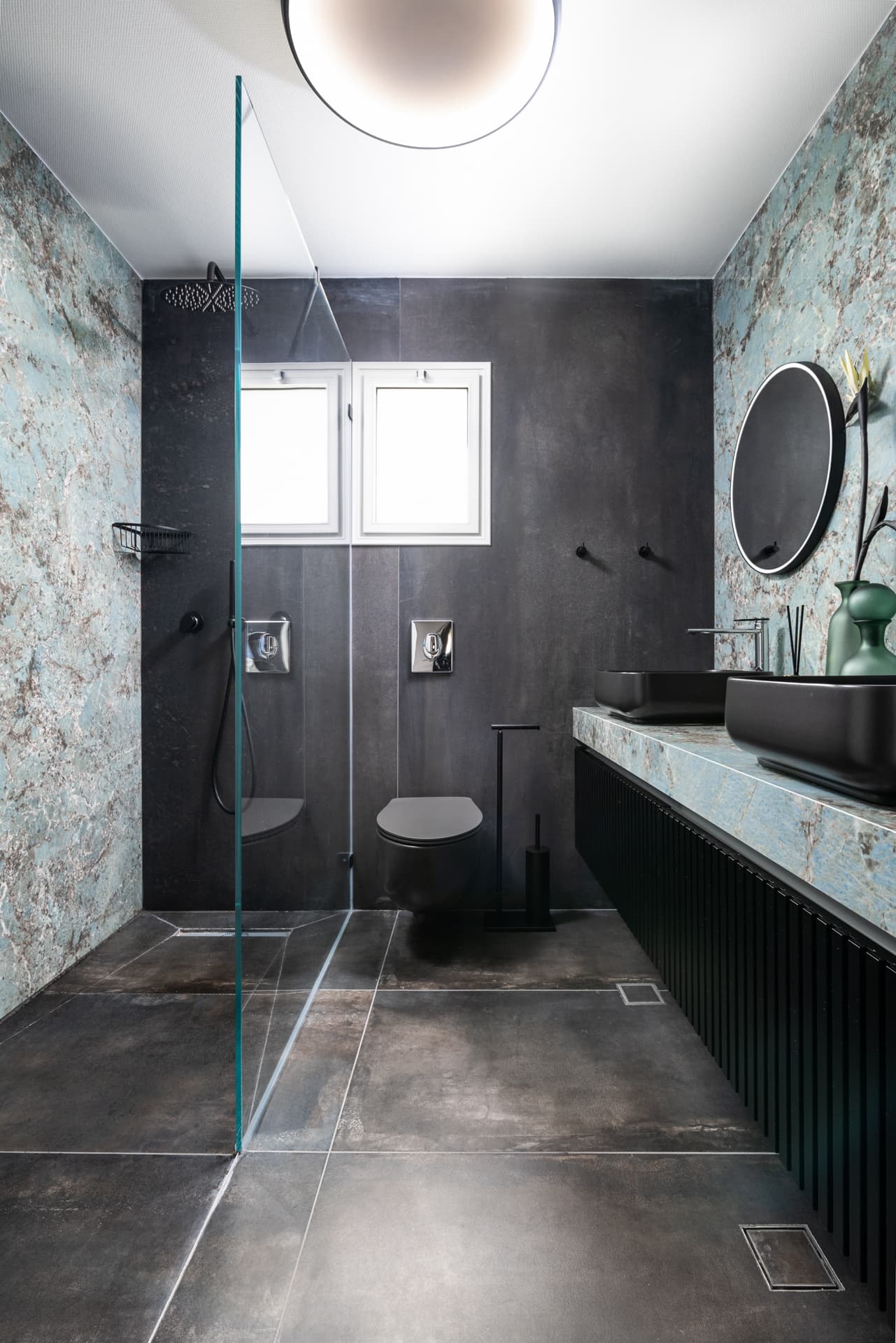 Charcoal walls, blue-green veined stone and a glass shower screen with black fixtures in the bathroom of Emperador Dark