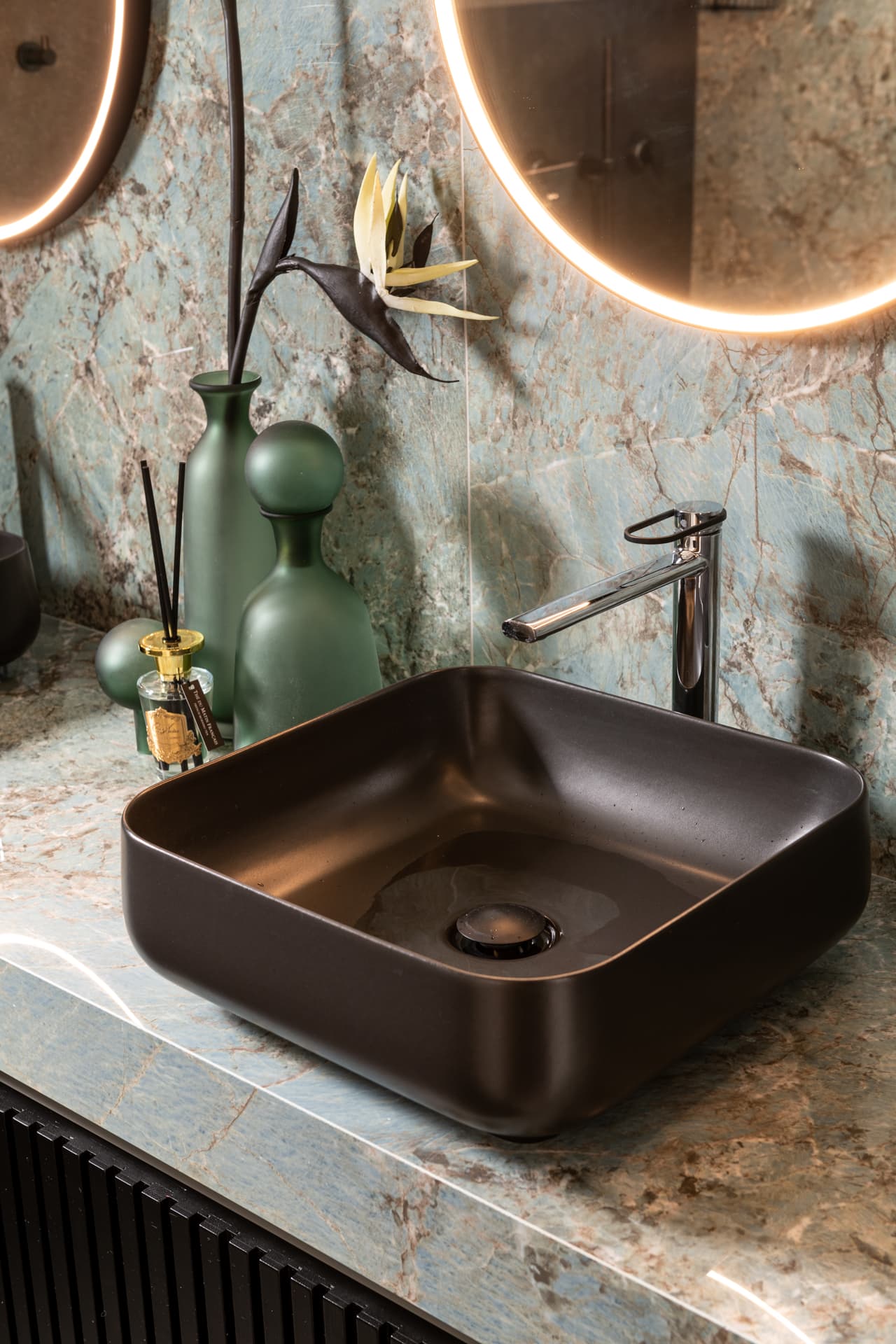 Matte black square vessel sink with a chrome faucet on a blue-green veined stone counter in the bathroom of Emperador Dark