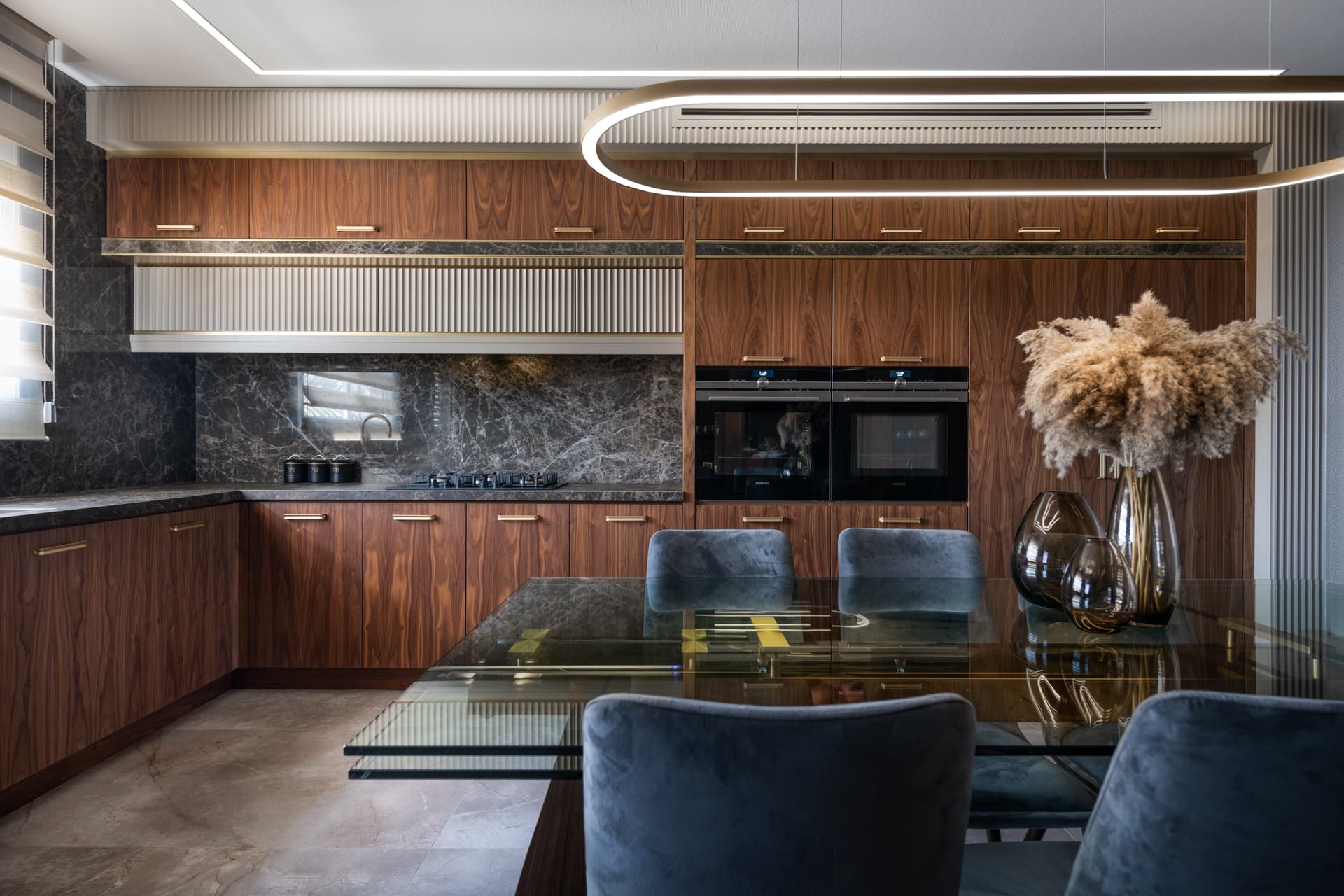 Walnut cabinets with brass pulls, a fluted cream cabinet band and a dark veined stone backsplash in the kitchen of Emperador Dark