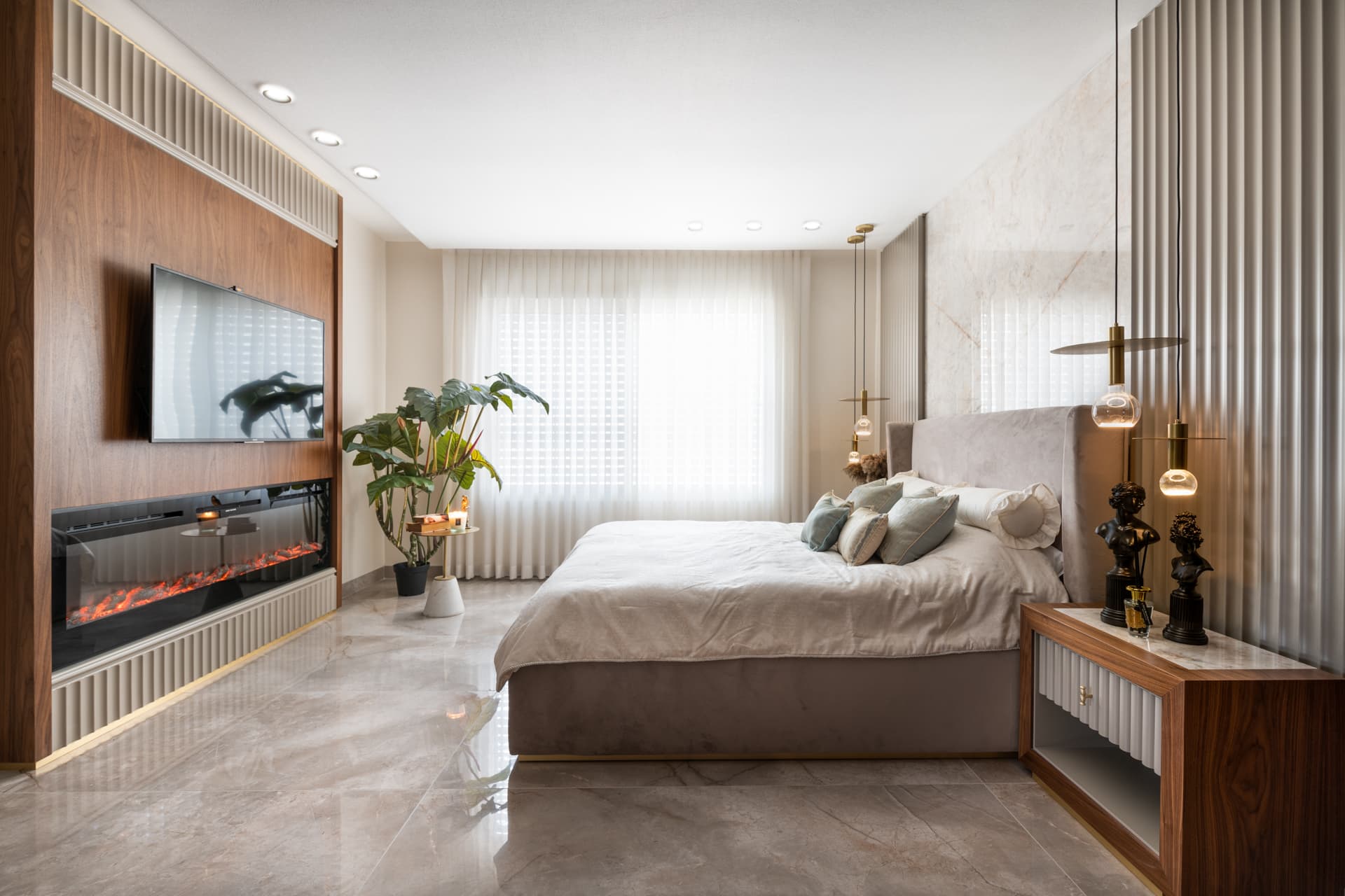 Upholstered bed facing a walnut media wall with a built-in electric fireplace in the master bedroom of Emperador Dark