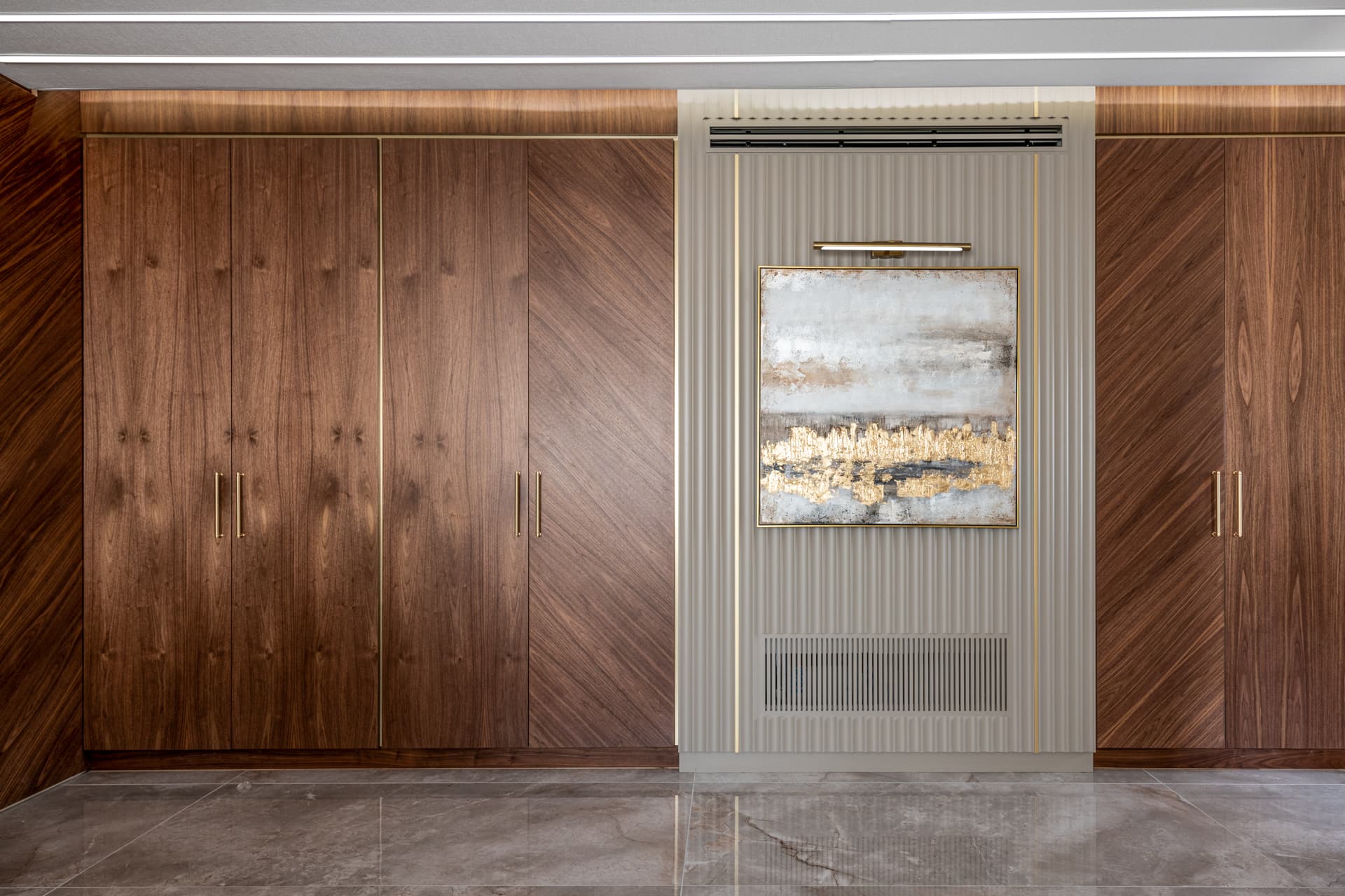 Walnut wardrobes with diagonal grain flank a fluted panel and gold-toned abstract painting in the master bedroom of Emperador Dark