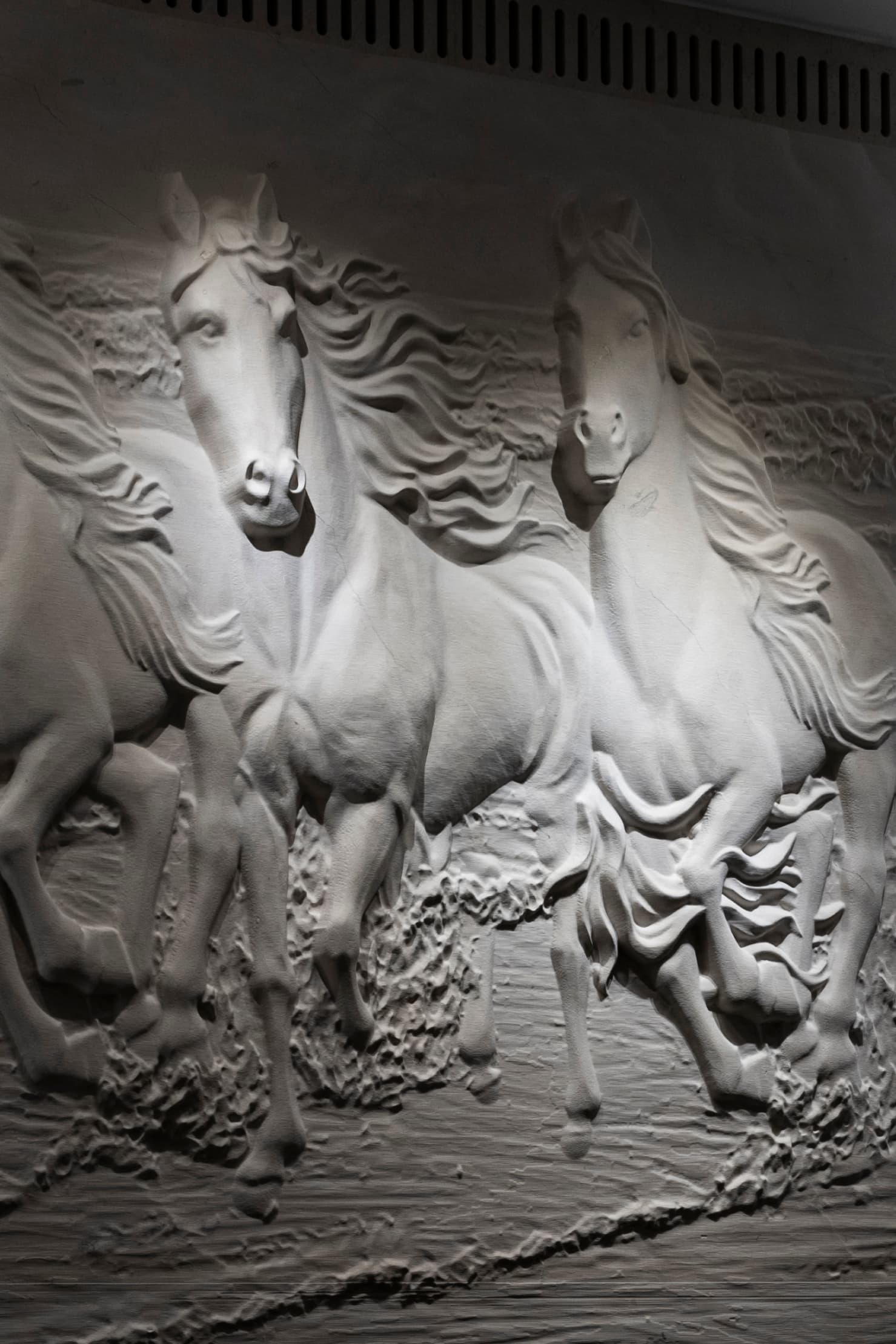 Close-up of galloping horses carved in the white plaster relief wall of the salon in Khayyal