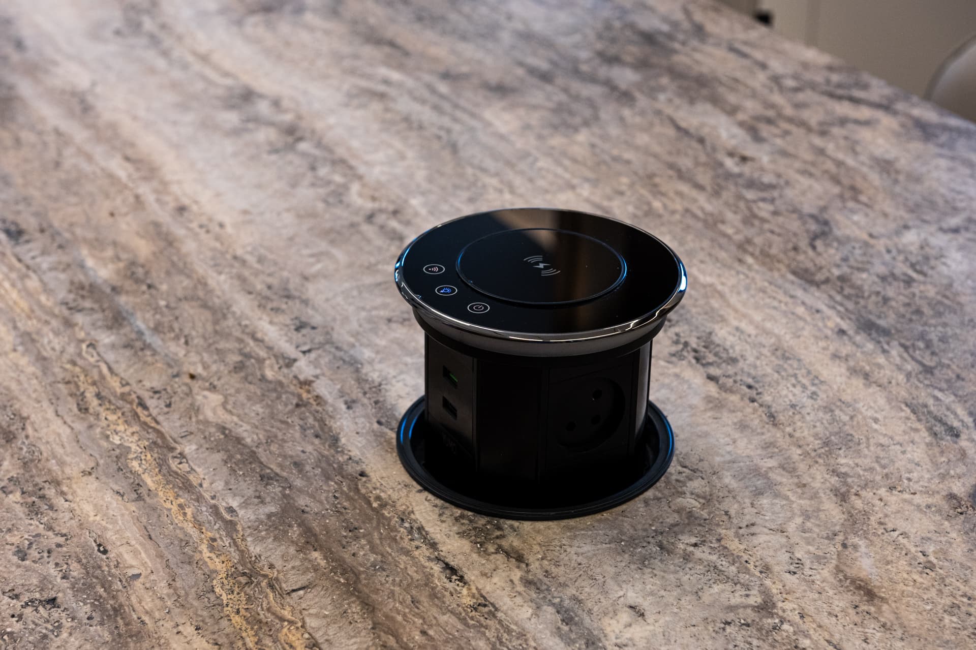 Pop-up black power socket set into a veined stone island top in the kitchen of Khayyal
