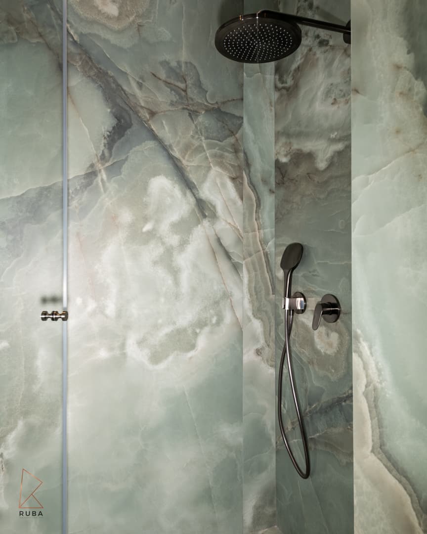 Shower with green onyx-look stone walls, a round black rain head and dark hand shower in the kids bathroom of Khayyal