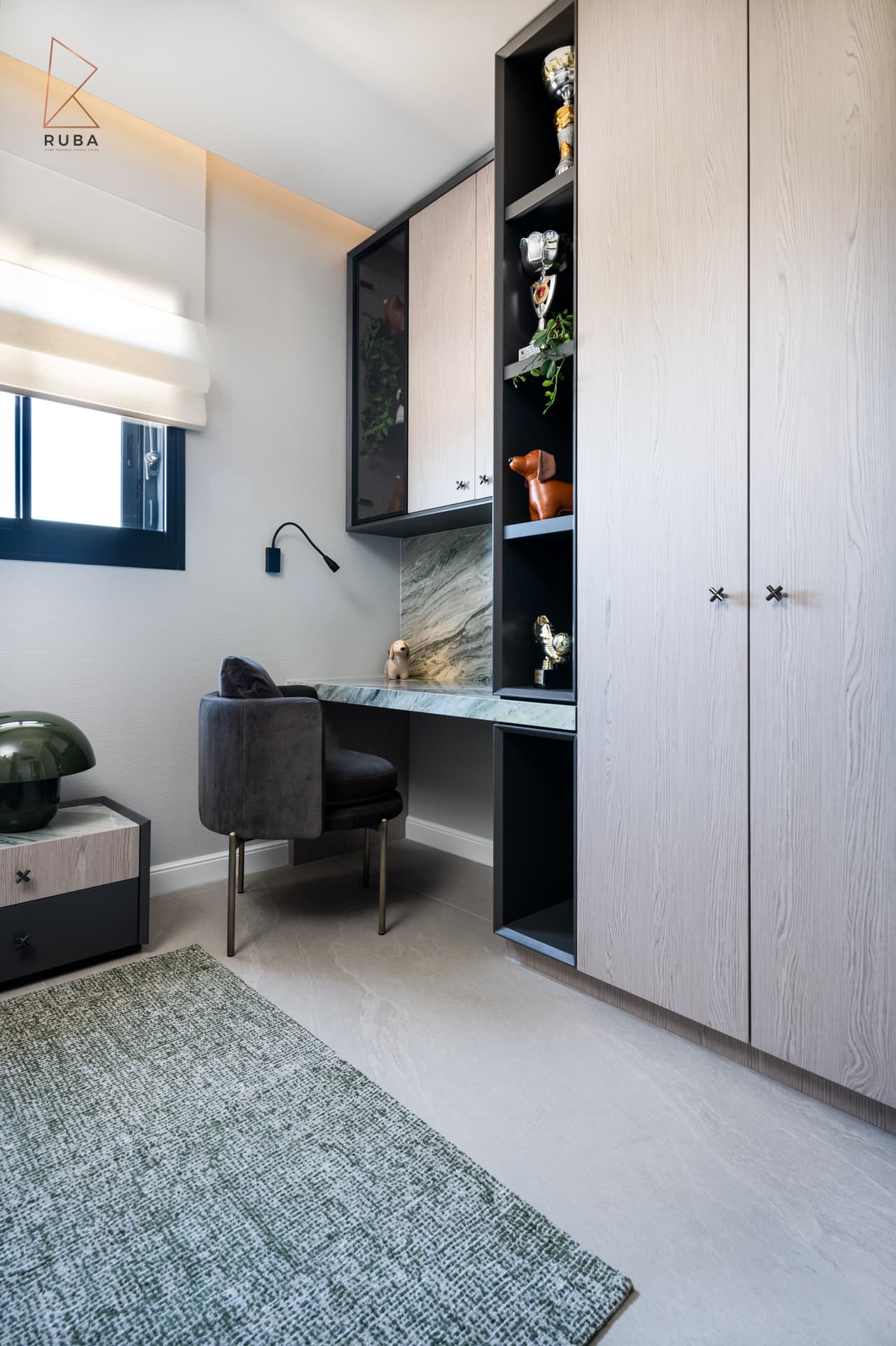 Study nook with a green veined stone desk, velvet chair and tall wardrobe with open display shelves in a kids room of Khayyal