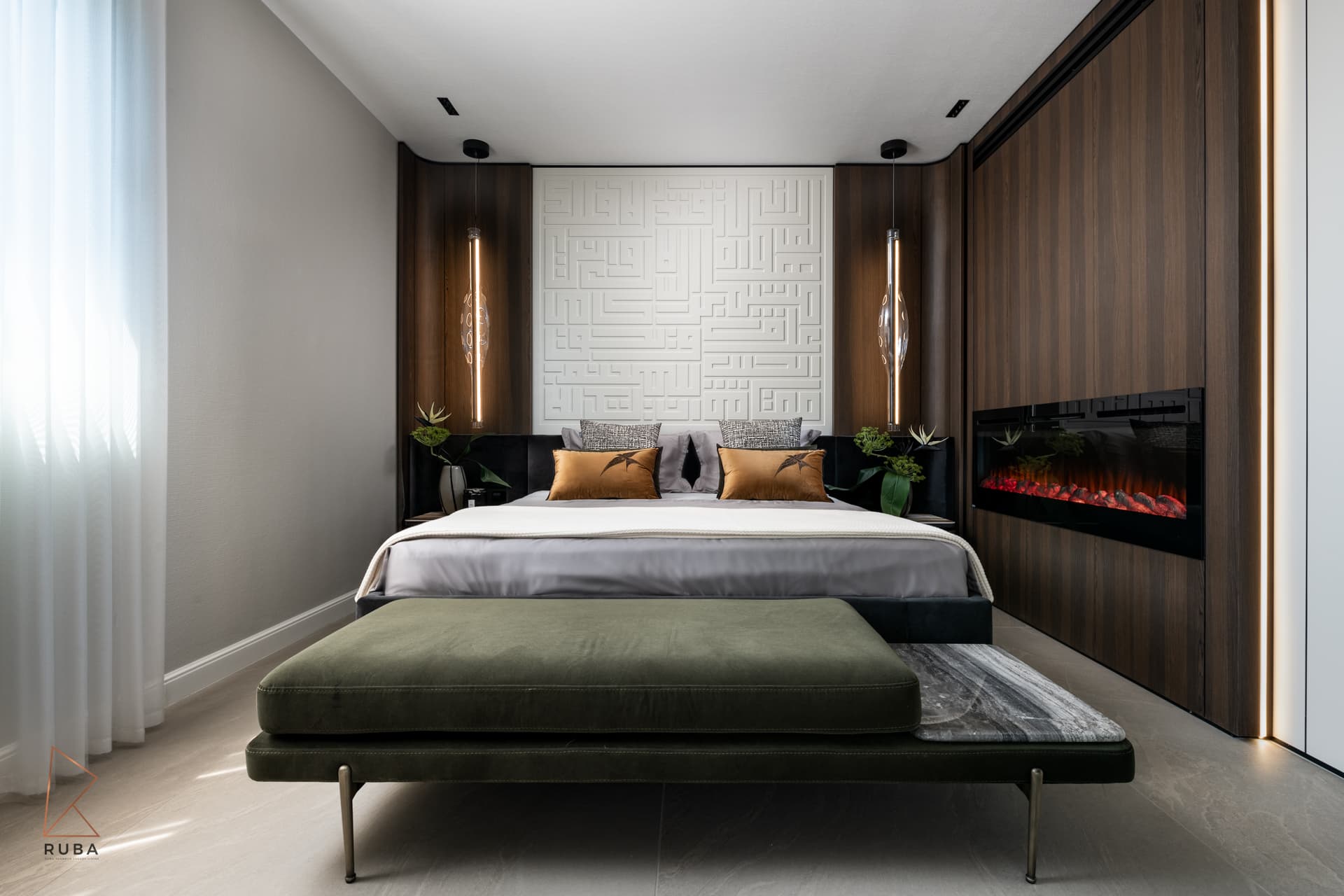 Bed against a white geometric relief headboard wall with walnut panels, pendant lights and a fireplace in the master bedroom of Khayyal