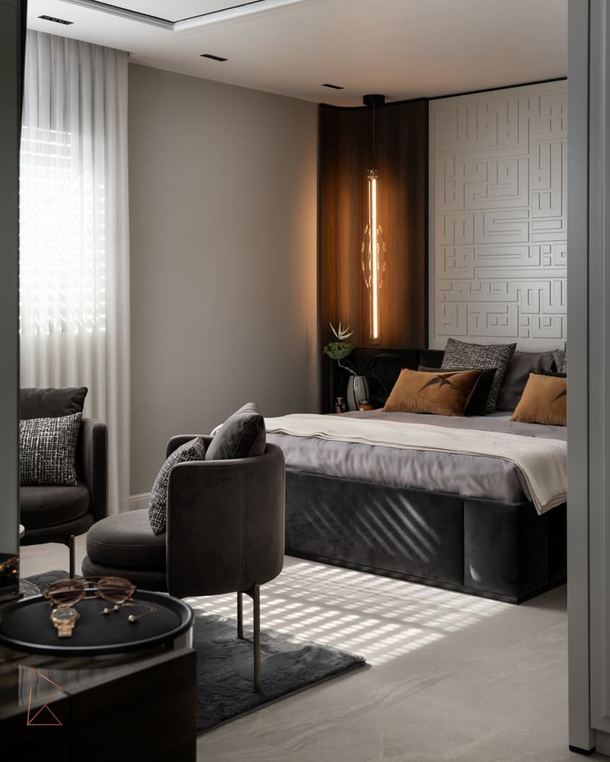 Doorway view of the bed with a velvet base, geometric relief wall and armchairs in dappled sunlight in the master bedroom of Khayyal