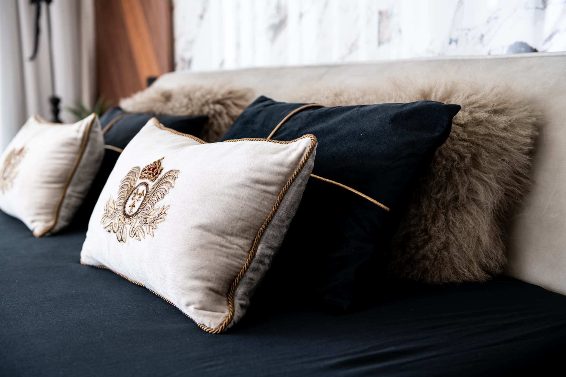 Embroidered cream velvet cushions with gold piping and fur pillows on the bed in the master bedroom of King David
