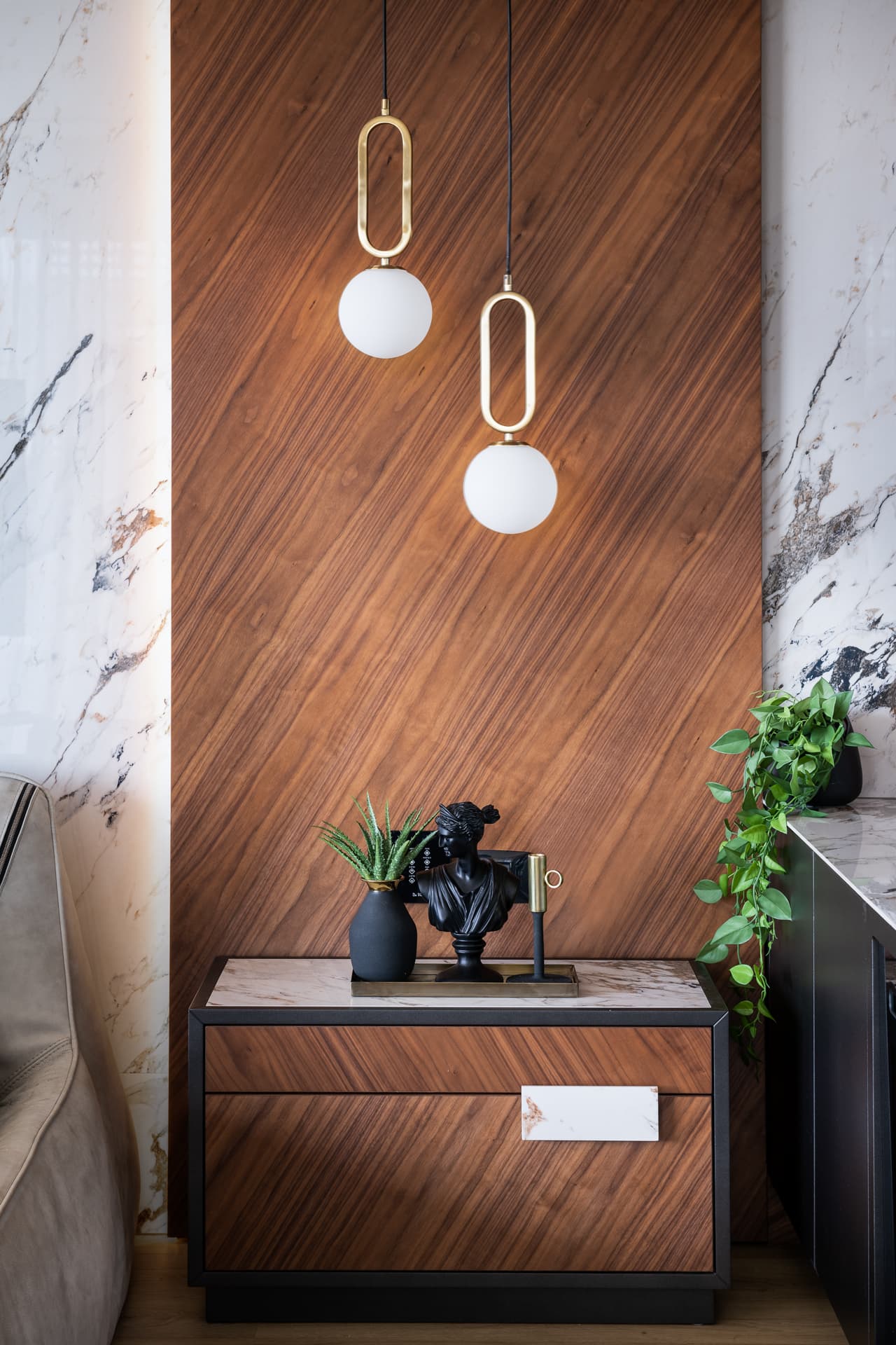 Brass-ring globe pendants over a walnut nightstand against a diagonal walnut panel in the master bedroom of King David