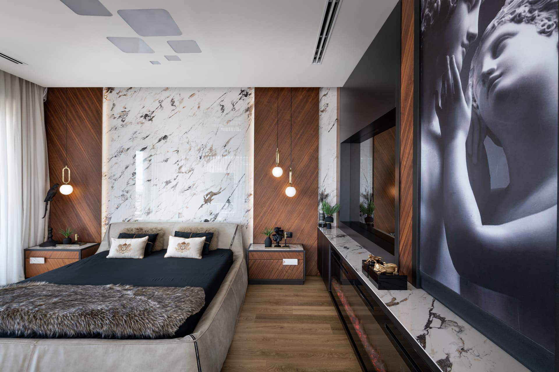 Bed framed by white veined stone and diagonal walnut panels with brass-ring globe pendants in the master bedroom of King David