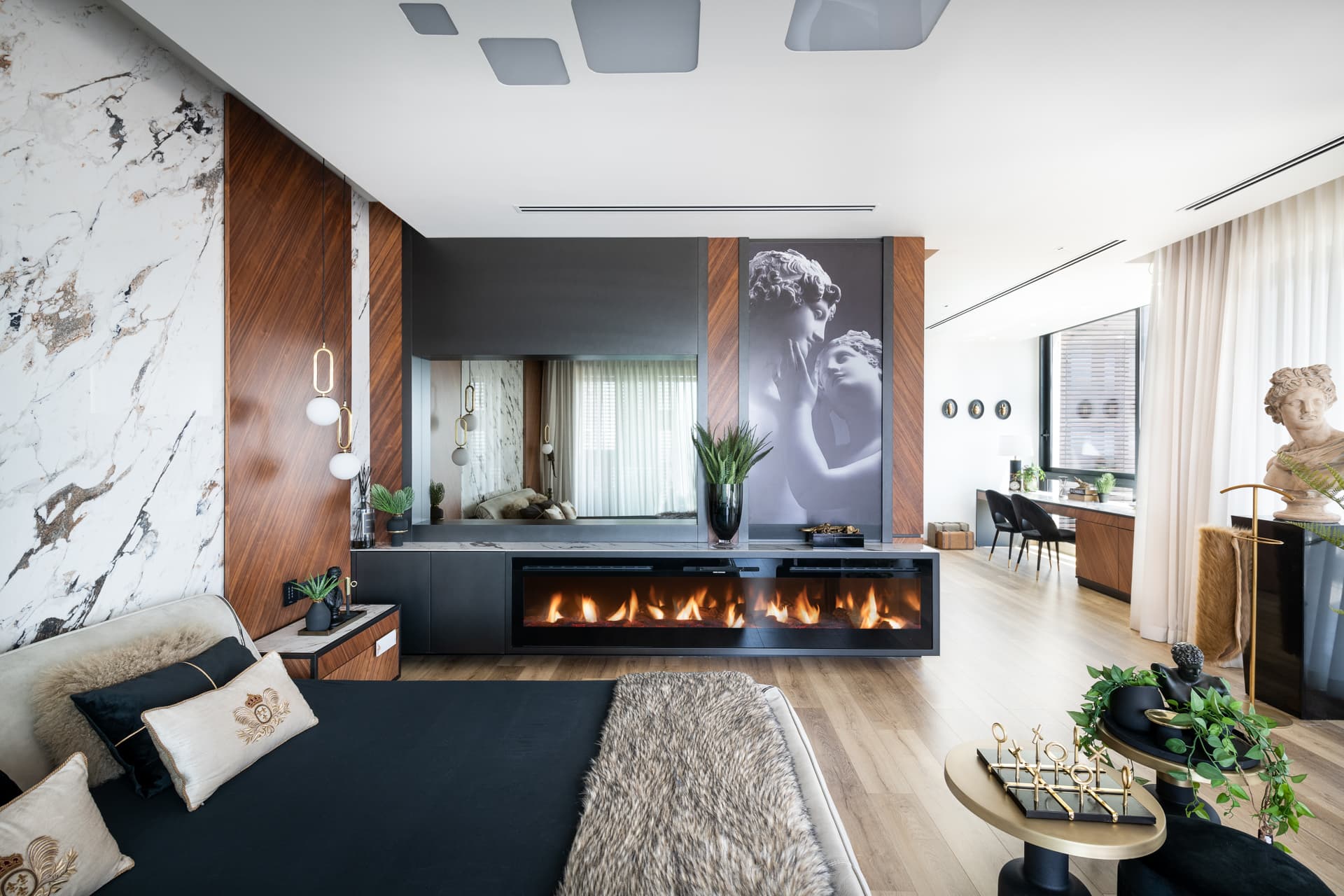 Long linear fireplace under a classical sculpture print, seen from the bed, in the master bedroom of King David