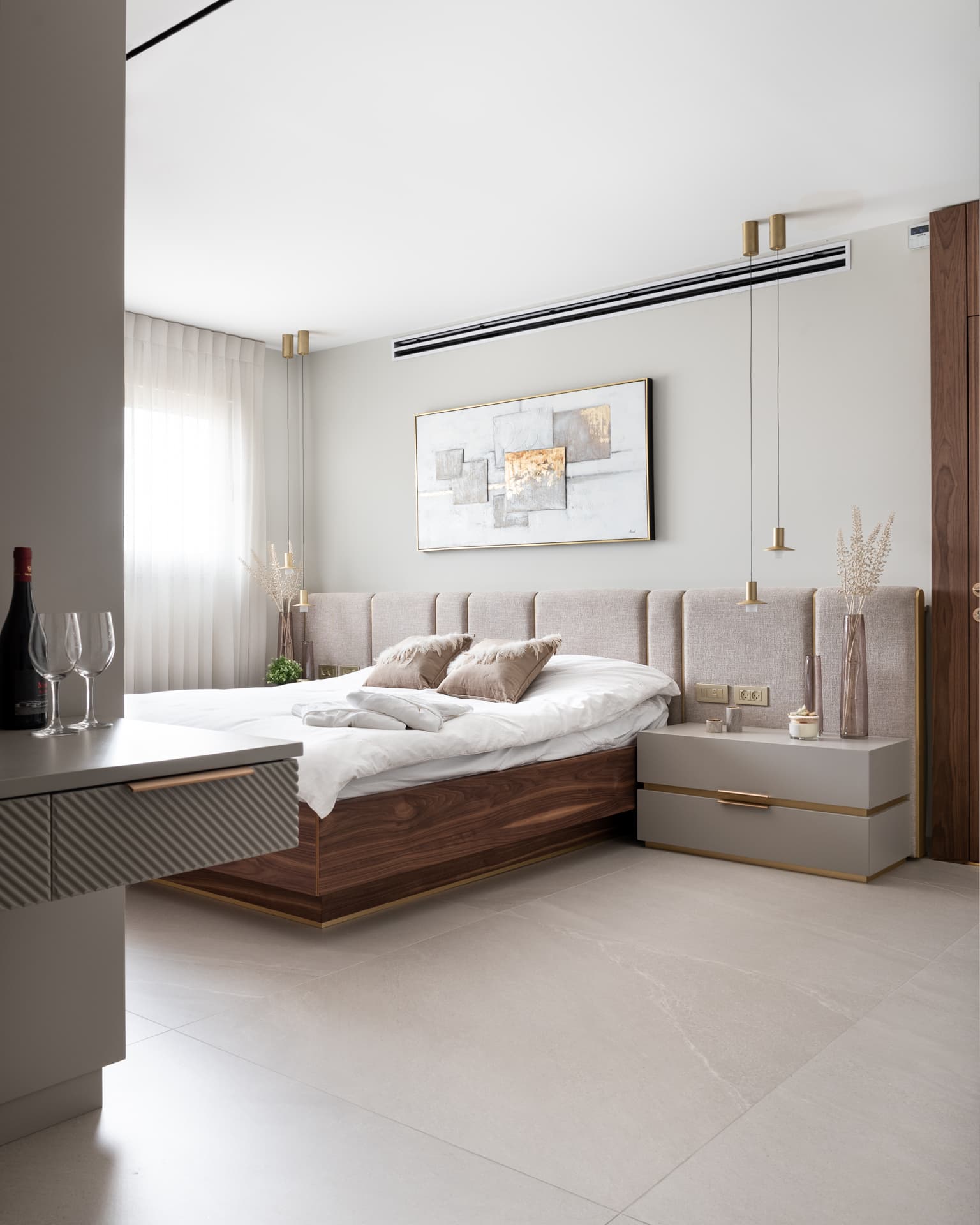 Bedroom with a floating walnut bed, a panelled upholstered headboard and brass pendant lights in Marquina