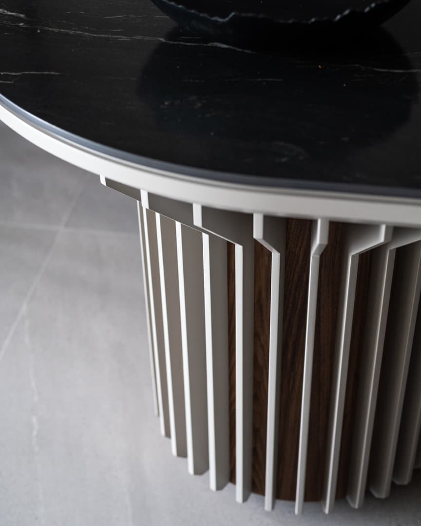 Fluted pale fins wrapped around a walnut pedestal beneath the black stone island top in the kitchen of Marquina
