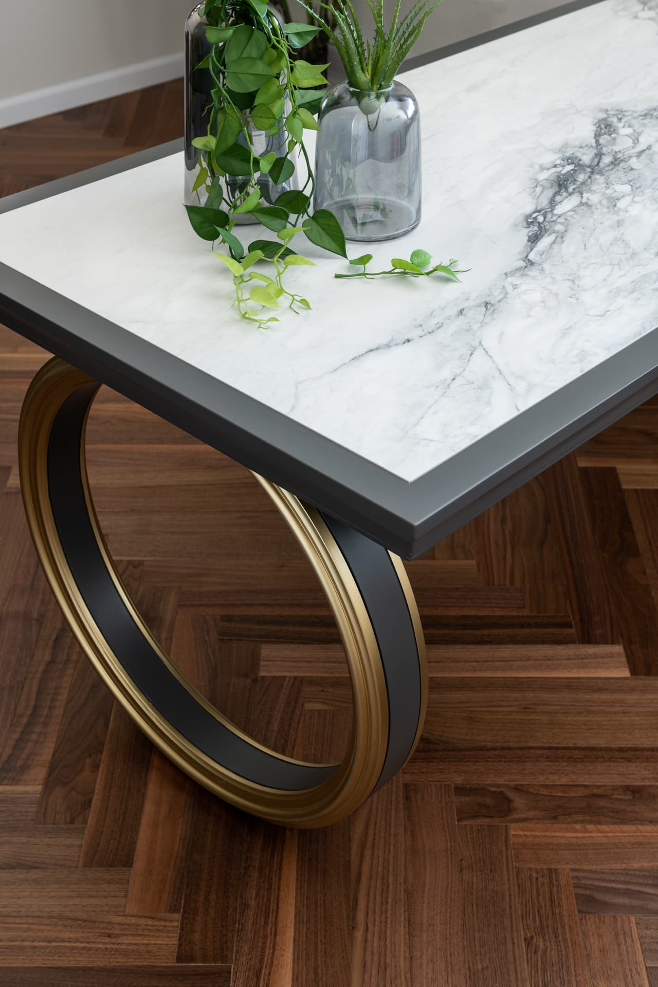 Gold ring-shaped leg beneath a charcoal-edged veined stone desktop in the consultation office of Moeen Clinic