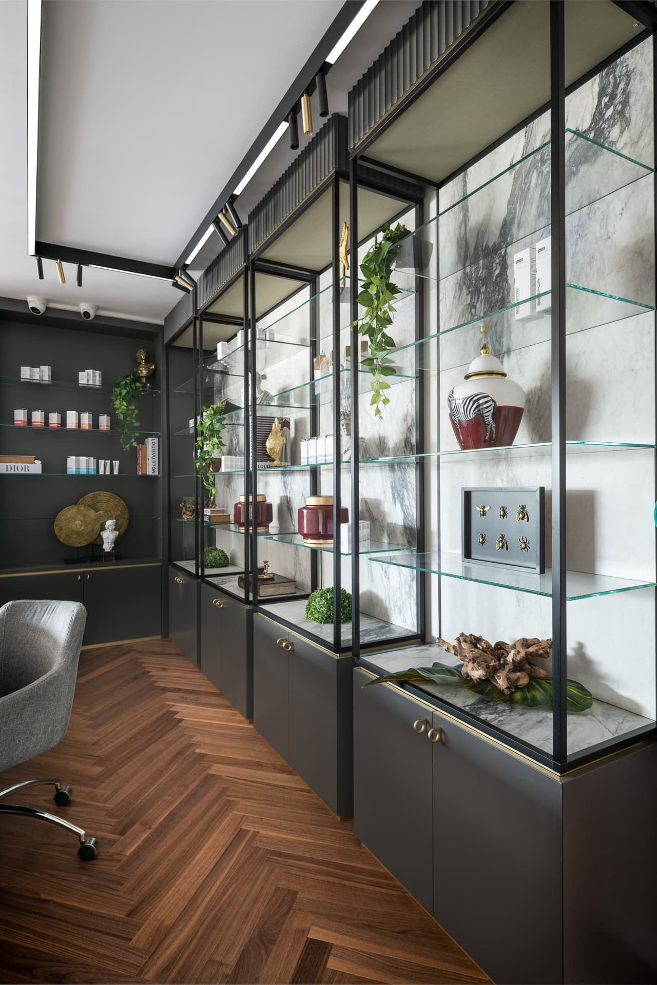 Black-framed glass display cabinets with veined stone backs and dark lower cupboards lining the reception of Moeen Clinic