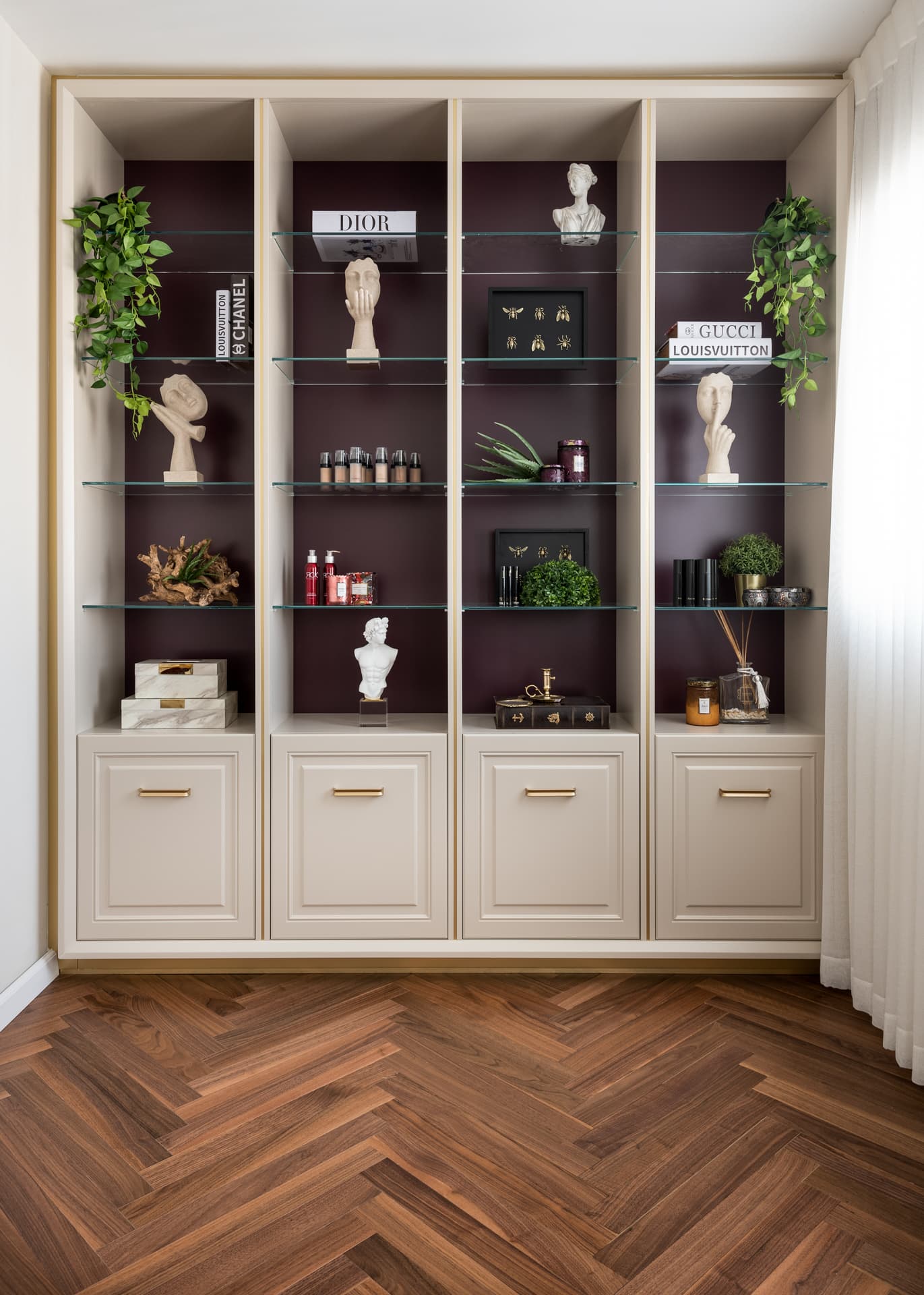 Cream display shelving with plum-backed glass shelves, bust sculptures and panelled cupboards at the vanity station of Moeen Clinic