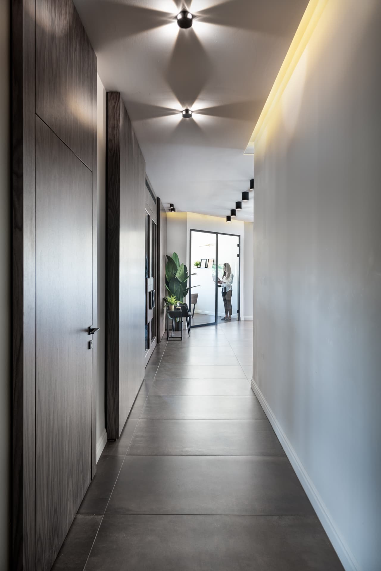 Narrow corridor with a dark wood flush door, grey stone floor tiles and star-patterned ceiling spotlights in the hallway of Othman Office 2