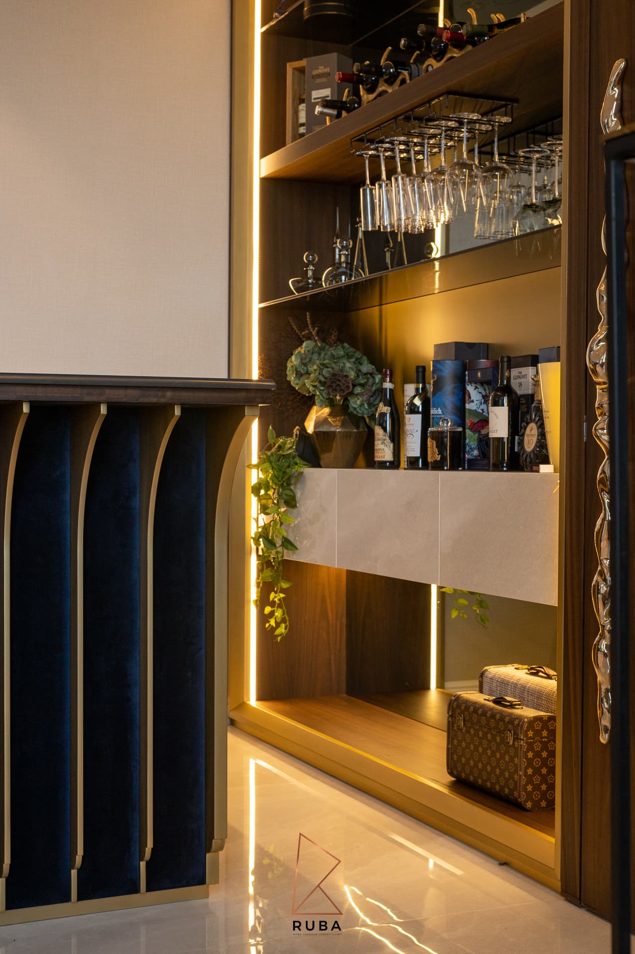 Side of the velvet bar counter beside lit shelving with hanging wine glasses and bottles in the bar of Patagonia