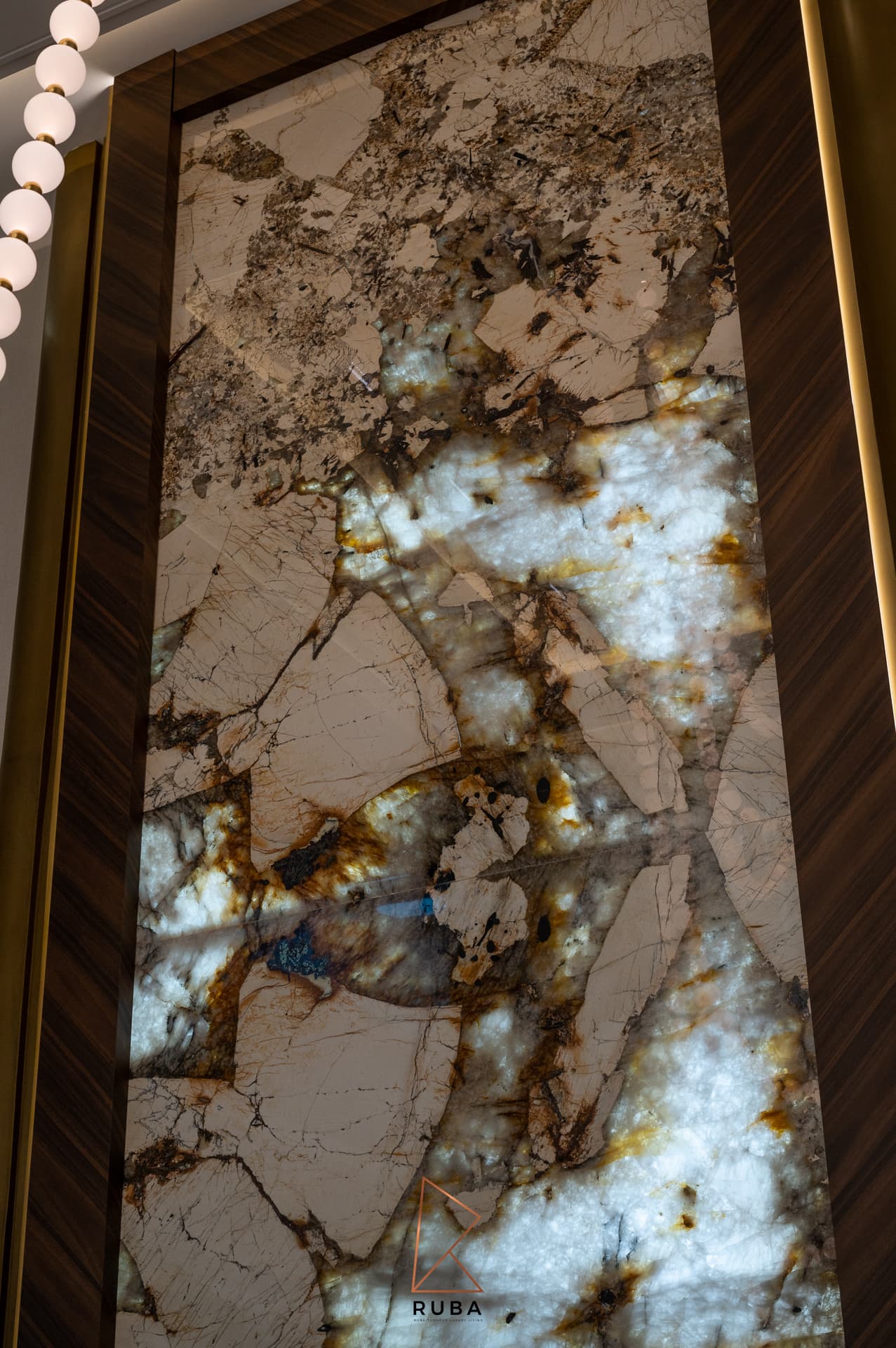 Backlit veined stone panel glowing through amber and blue veins inside a walnut frame in the living room of Patagonia