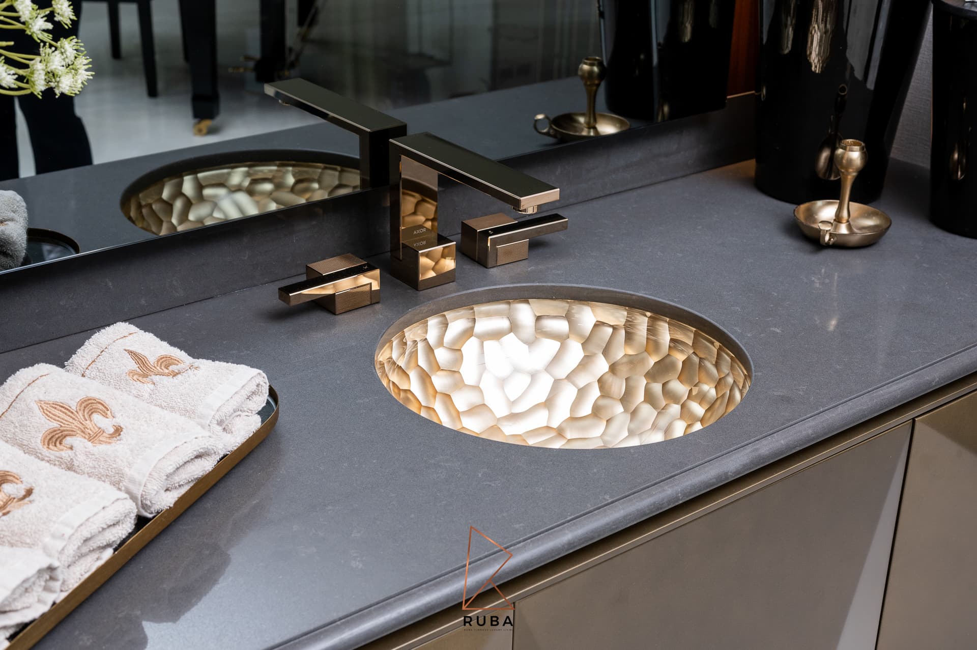 Hammered brass undermount basin with a square bronze faucet on a dark stone counter in the entrance of Patagonia