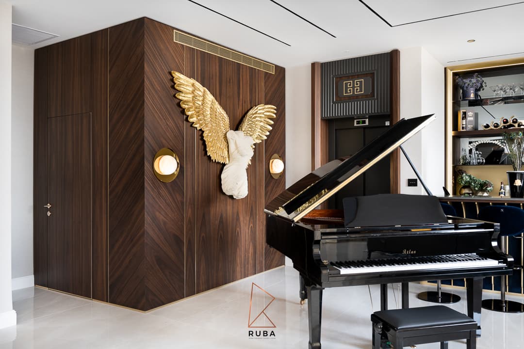 Chevron walnut corner wall with a gold-winged torso sculpture and globe sconces behind a grand piano in Patagonia